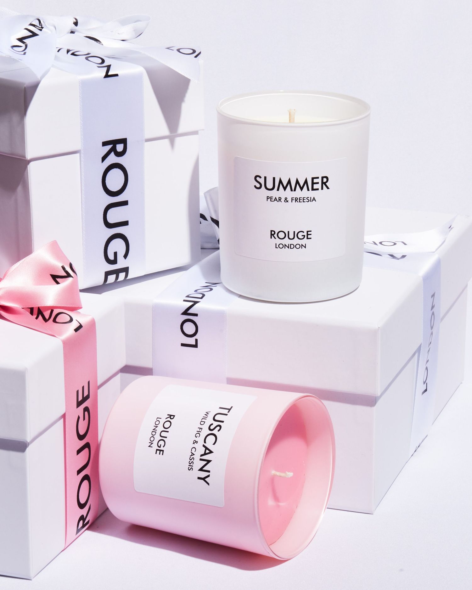 Minimalist white and pink packaging for Rouge London candle collection on clean background.