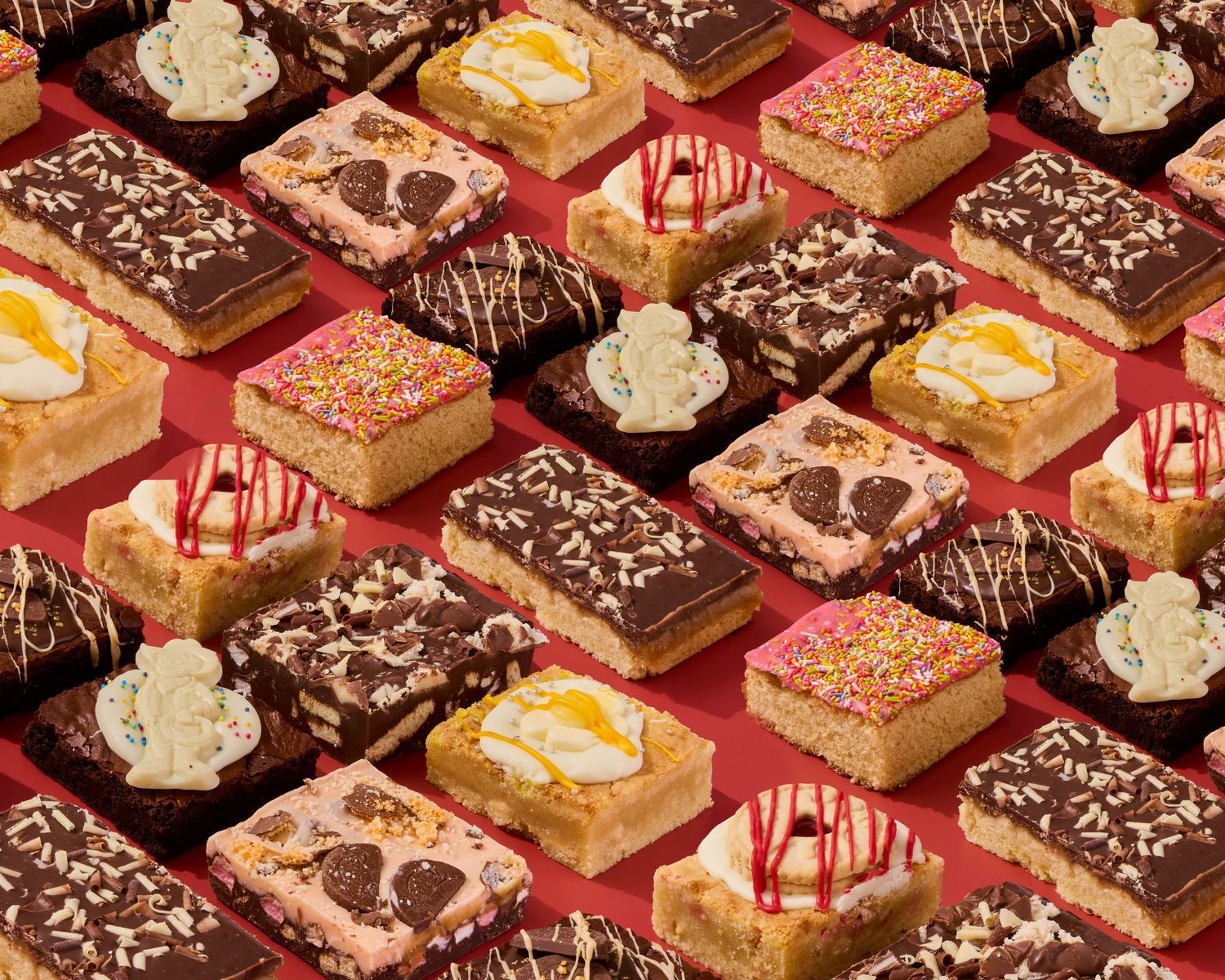 Rows of decorated dessert bars with chocolate drizzle and sprinkles arranged in a pattern.