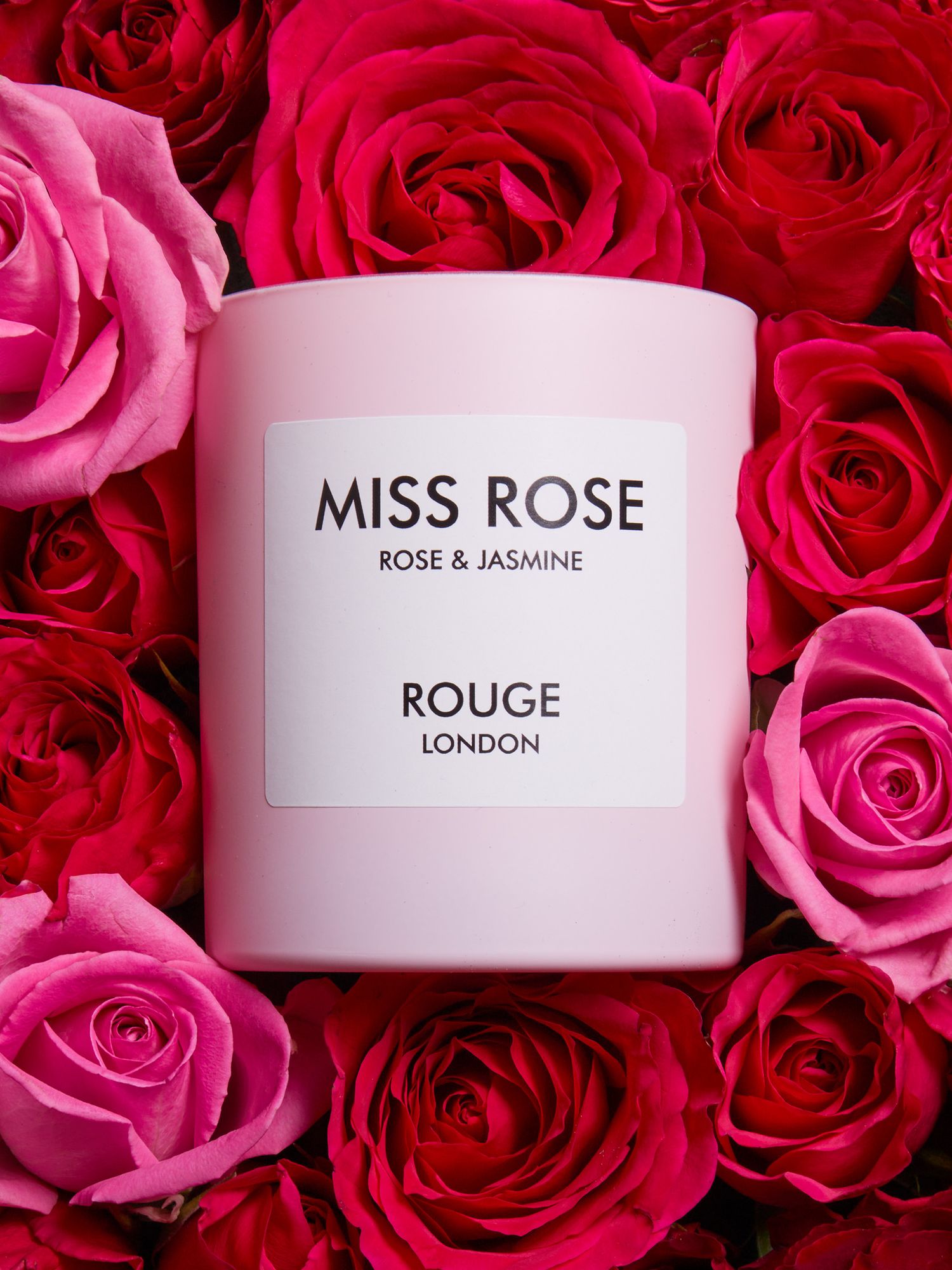 Miss Rose fragrance by Rouge London displayed among red and pink rose petals.