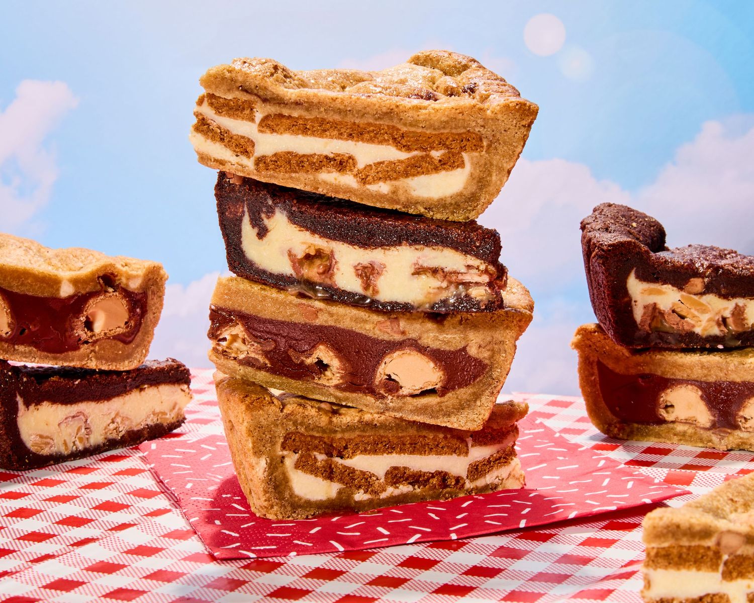 Multiple chocolate and vanilla dessert bars arranged in a line on a red and white checkered tablecloth.