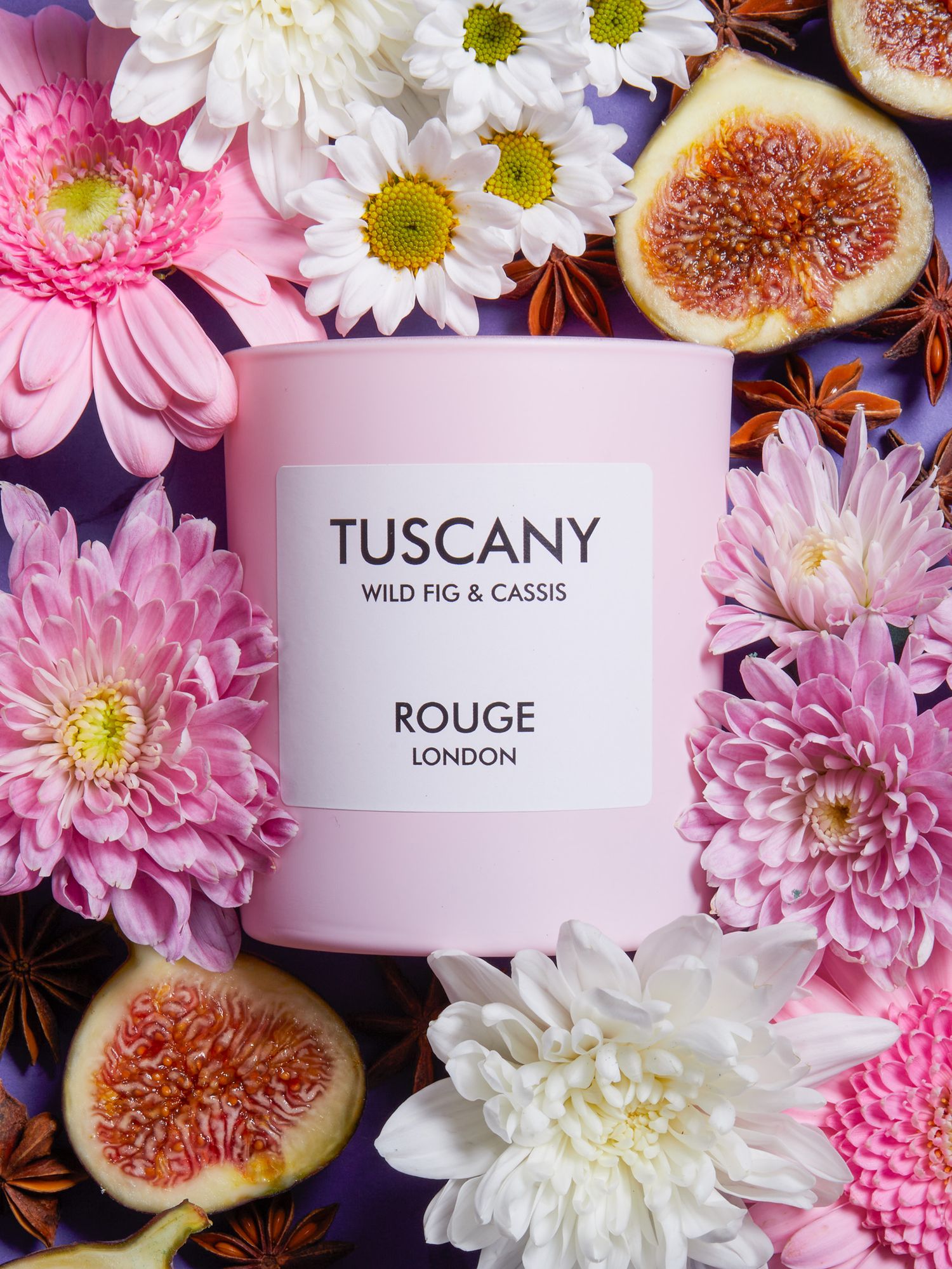 White candle containers surrounded by pink flowers and fresh figs in romantic styling.