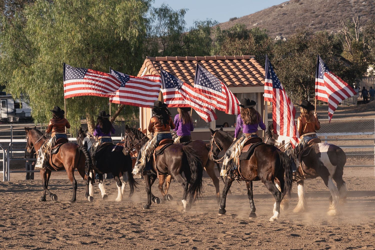 Riders carrying American flags perform in formation at an equestrian event.