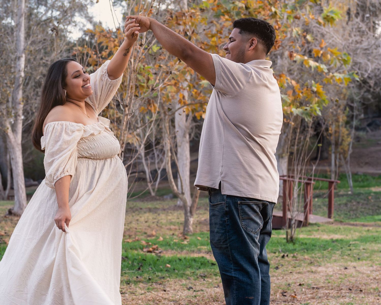 Couple dancing together in an outdoor setting with fall foliage in the background.