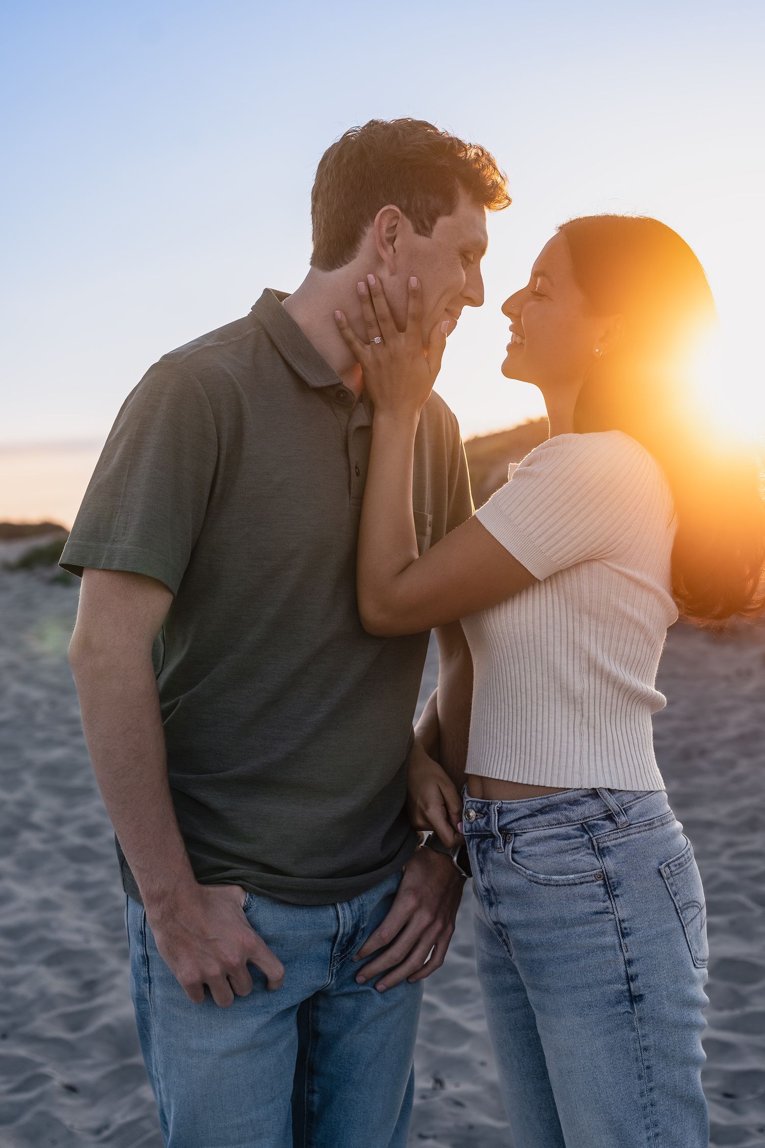 A couple shares an intimate moment on the beach during golden hour.