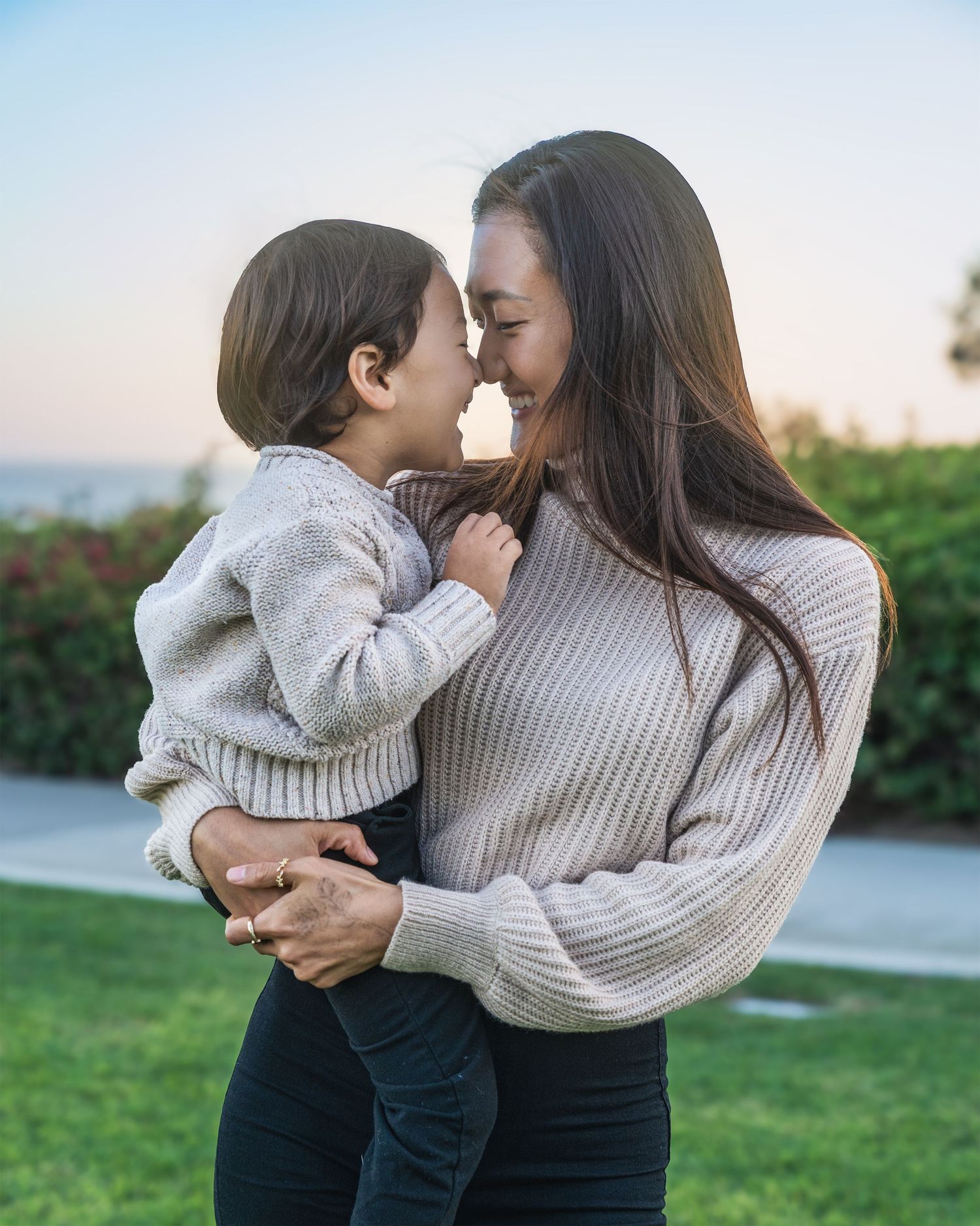 Mother and child in matching sweaters sharing tender moments outdoors.