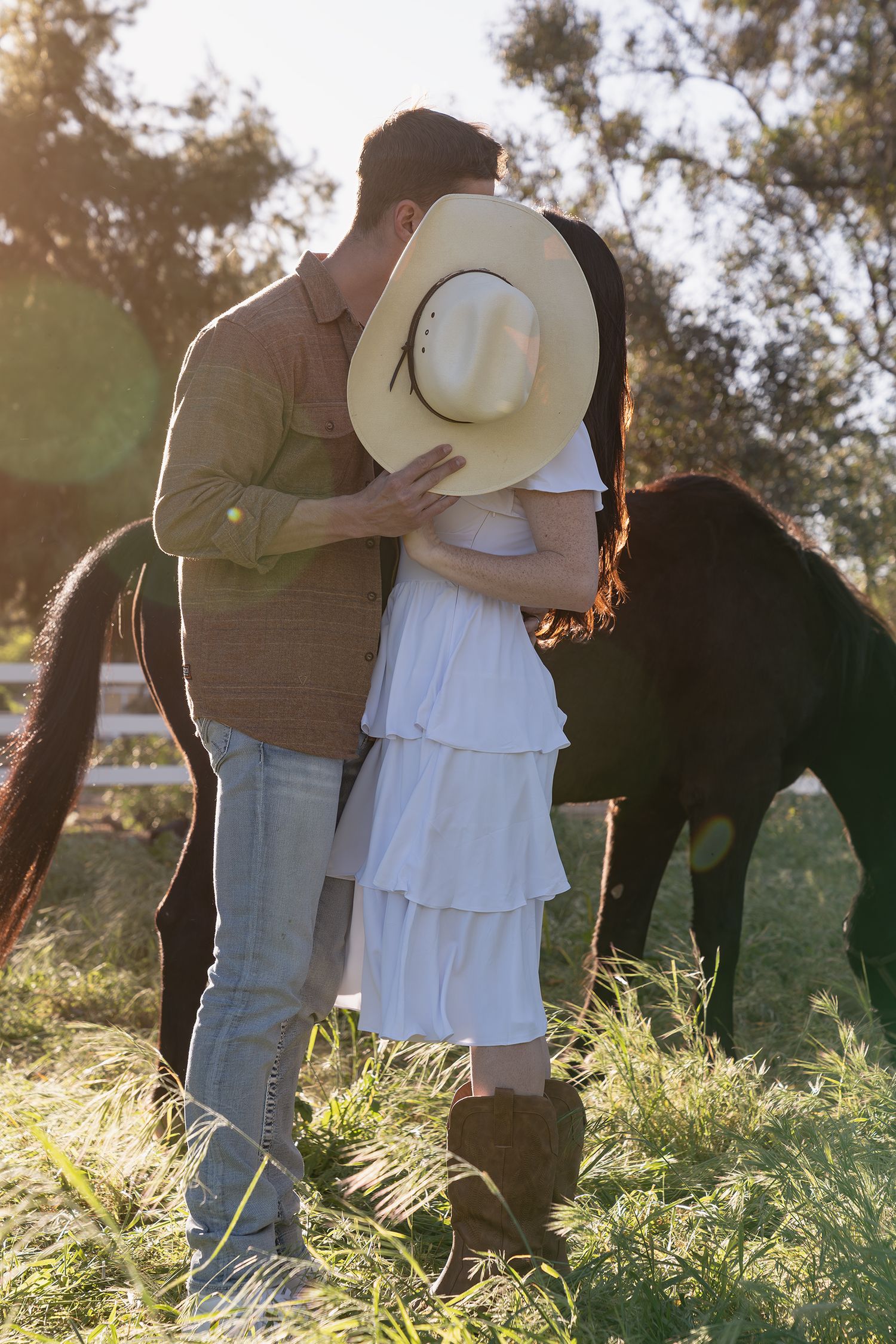 A couple embraces in a sunlit meadow with tall grass during golden hour.