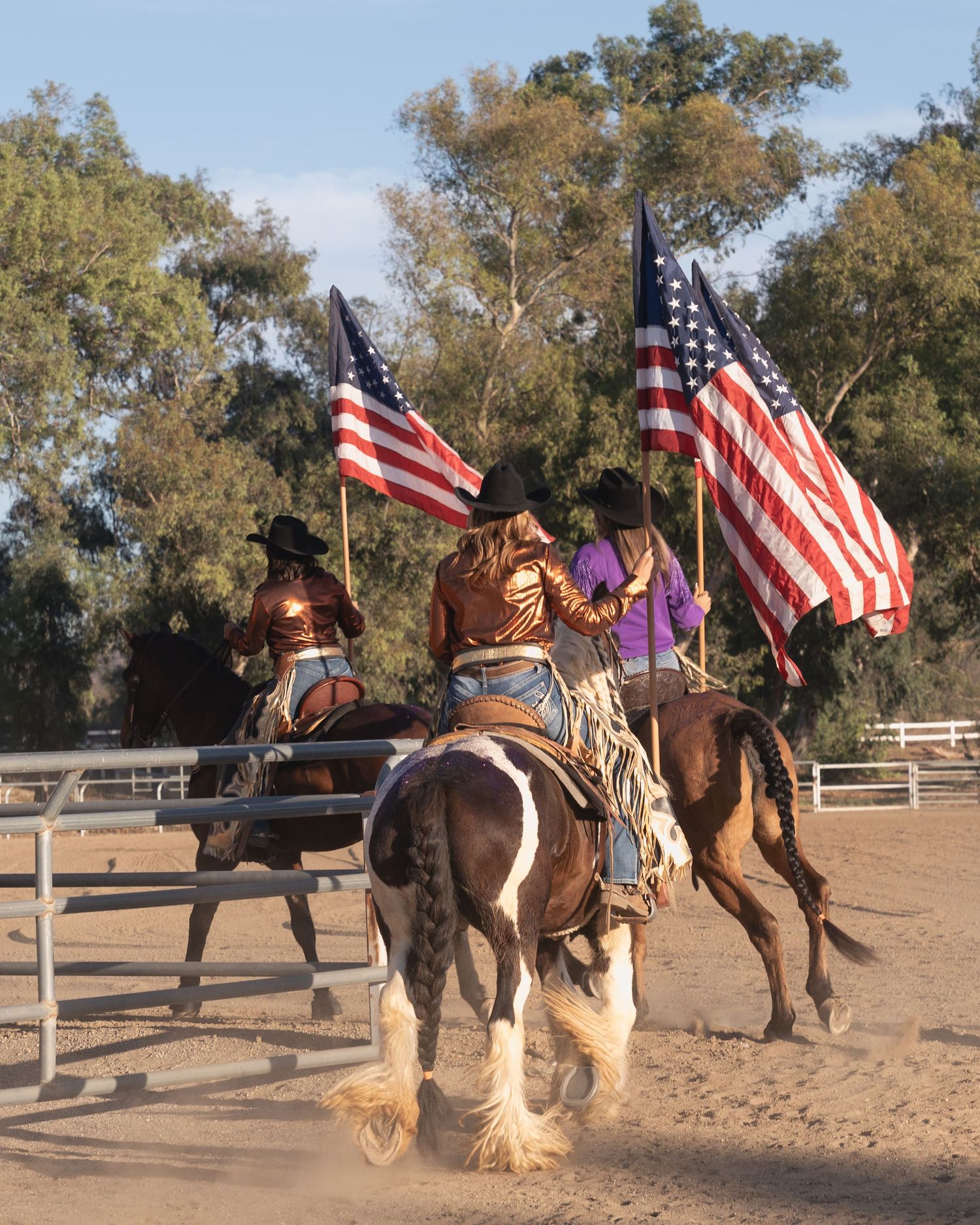 Equestrian team carries American flags while riding horses in formation.