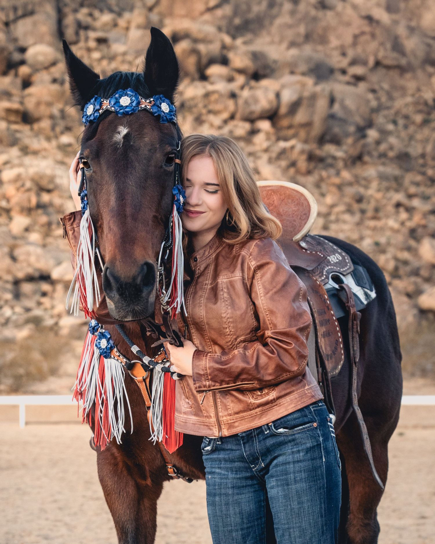 A horse with red white and blue tack poses in a desert setting.