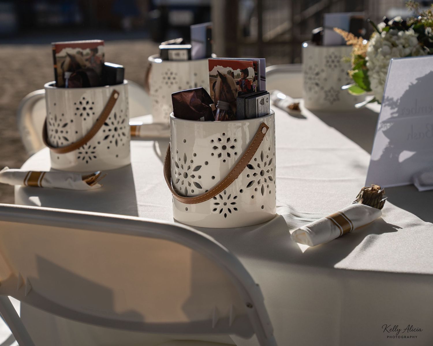 White ceramic lanterns with decorative cutout patterns displayed in a row on a table.