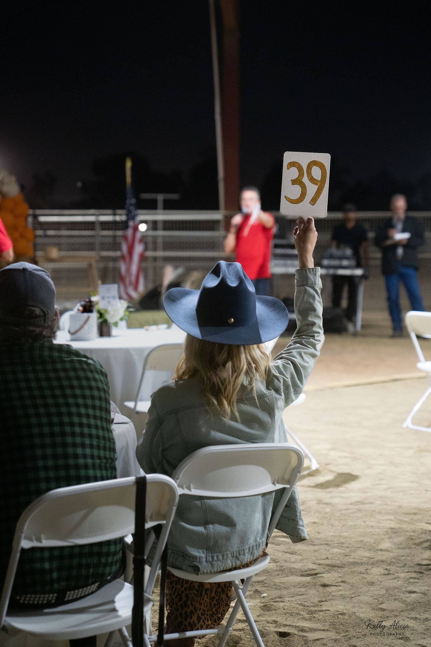 A person wearing a hat sits in a white folding chair at an outdoor event, shown in a sequence of similar views.