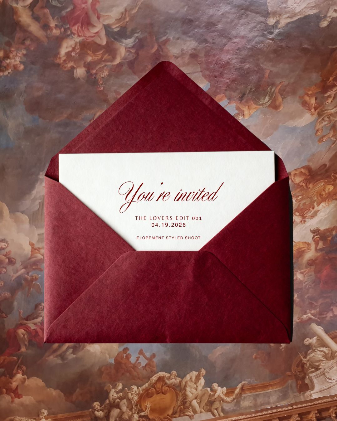 Elegant burgundy envelope with white invitation card reading 'You're invited' on a marbled background.