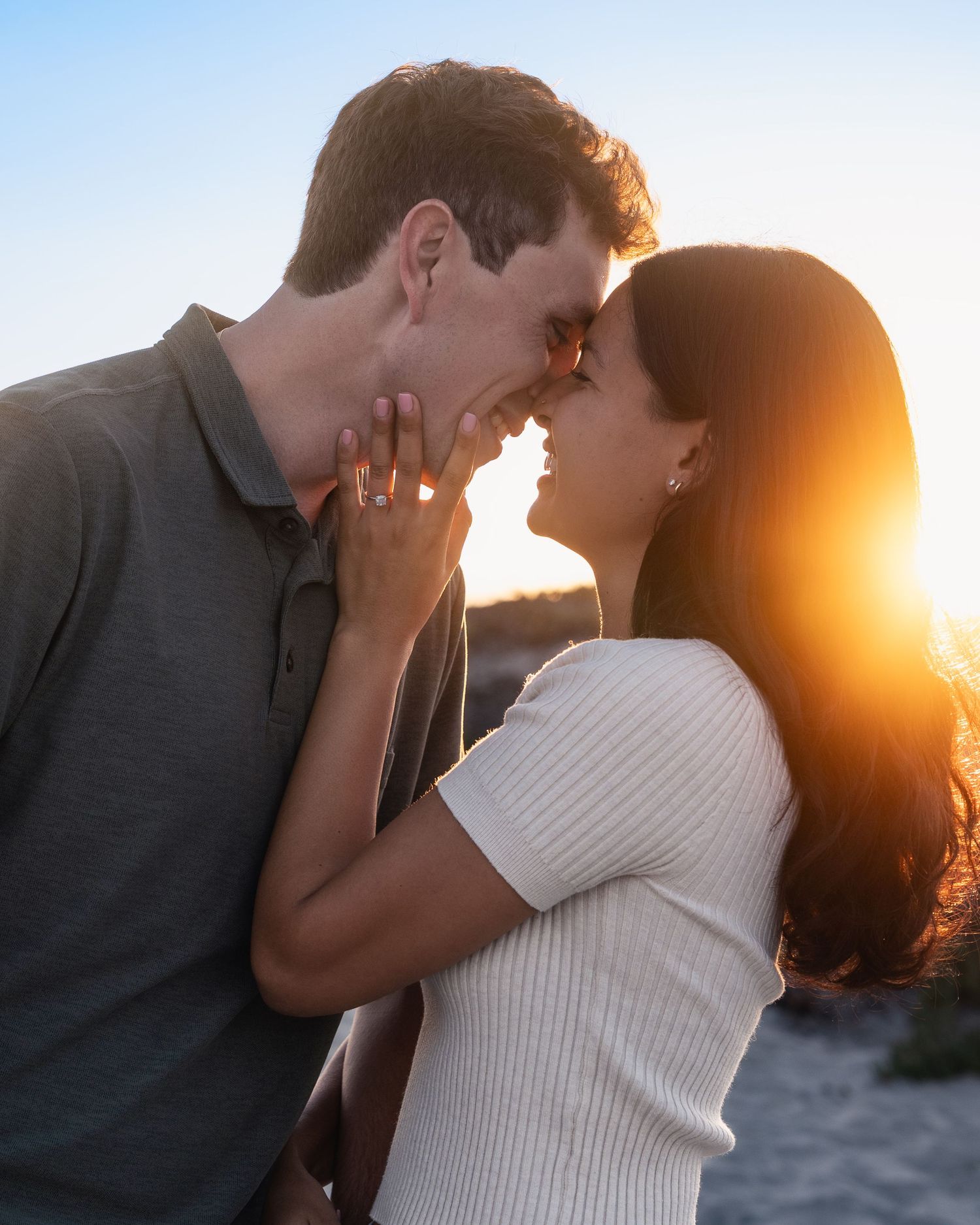 Couple sharing intimate moment at sunset with golden light behind them.