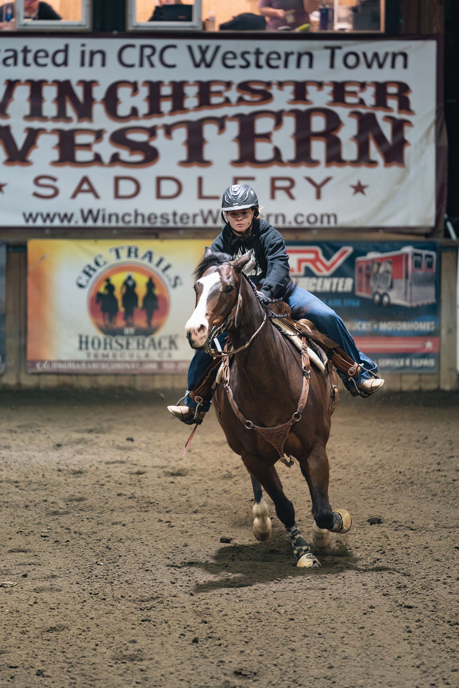 Horses and riders competing in western rodeo event with Winchester Western signage visible.
