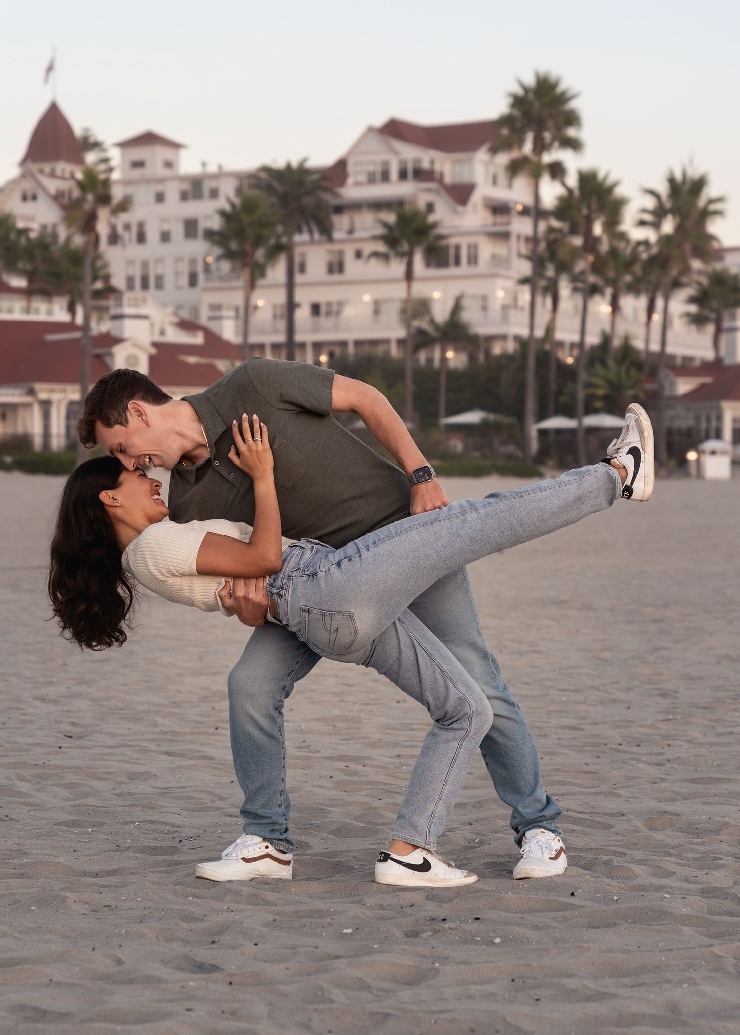 A couple performs a dramatic dance dip pose sequence on the beach.