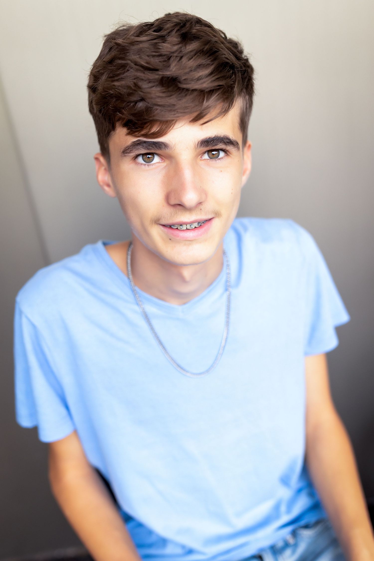 Portrait series showing casual expressions in a light blue t-shirt against a neutral background.