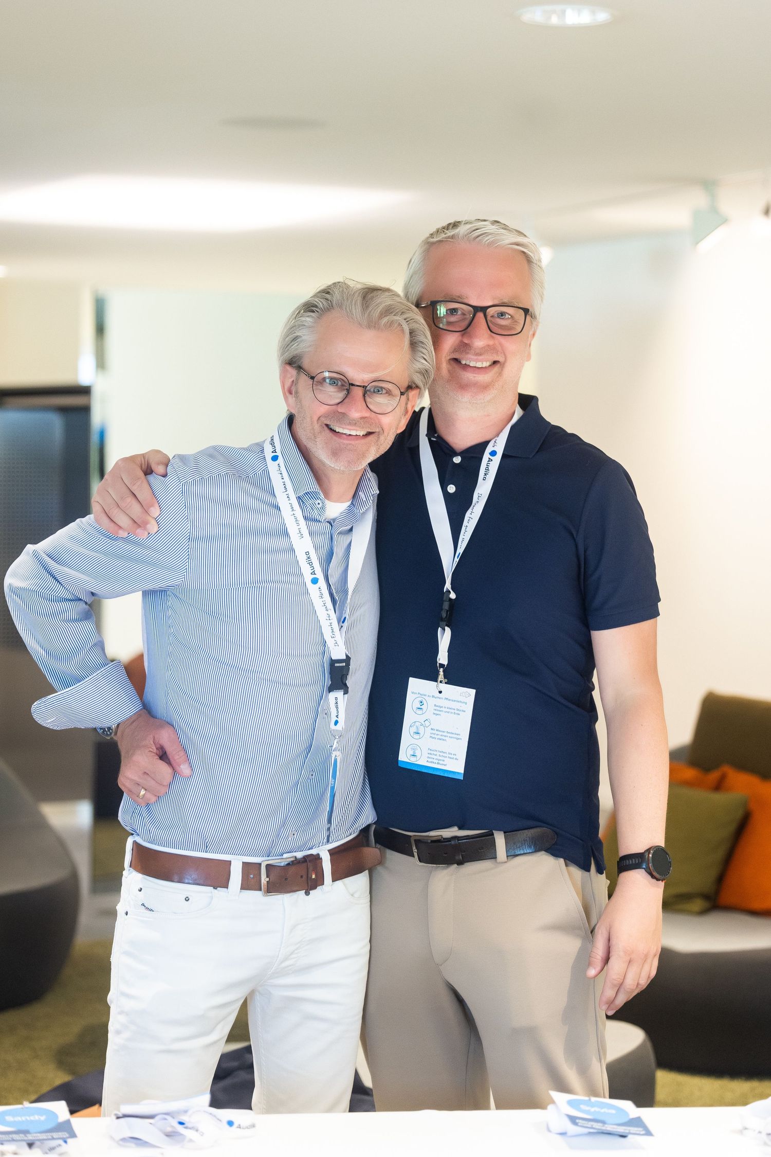 Two conference attendees in business attire pose together at a professional event.