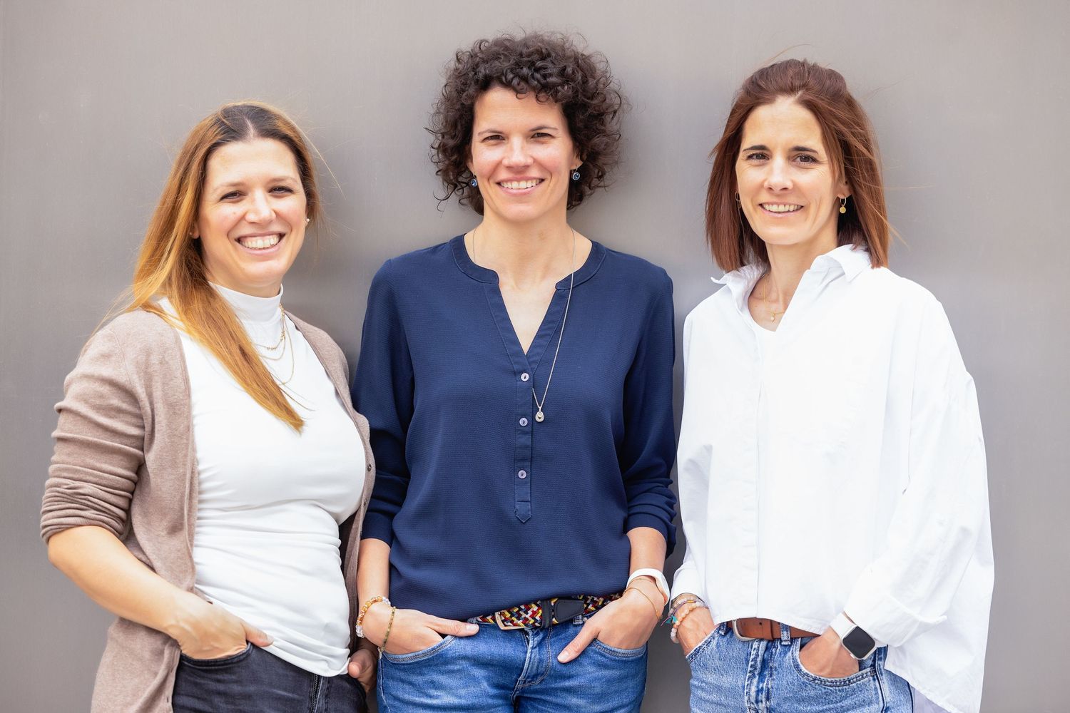 Professional team members posing against neutral background in business casual attire.