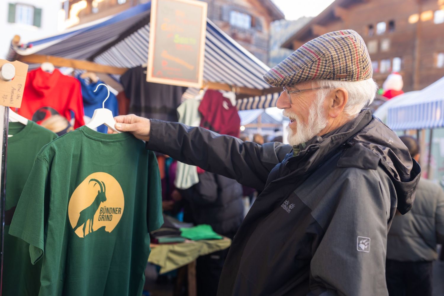Person in winter coat reaching toward green merchandise at an outdoor market.