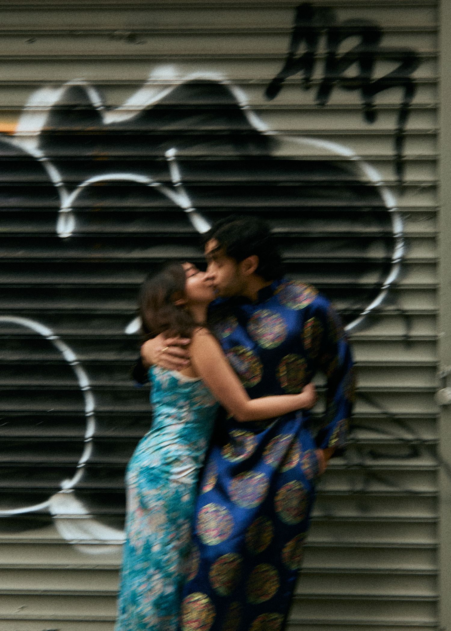 Couple embracing in front of a city mural during an editorial engagement session.