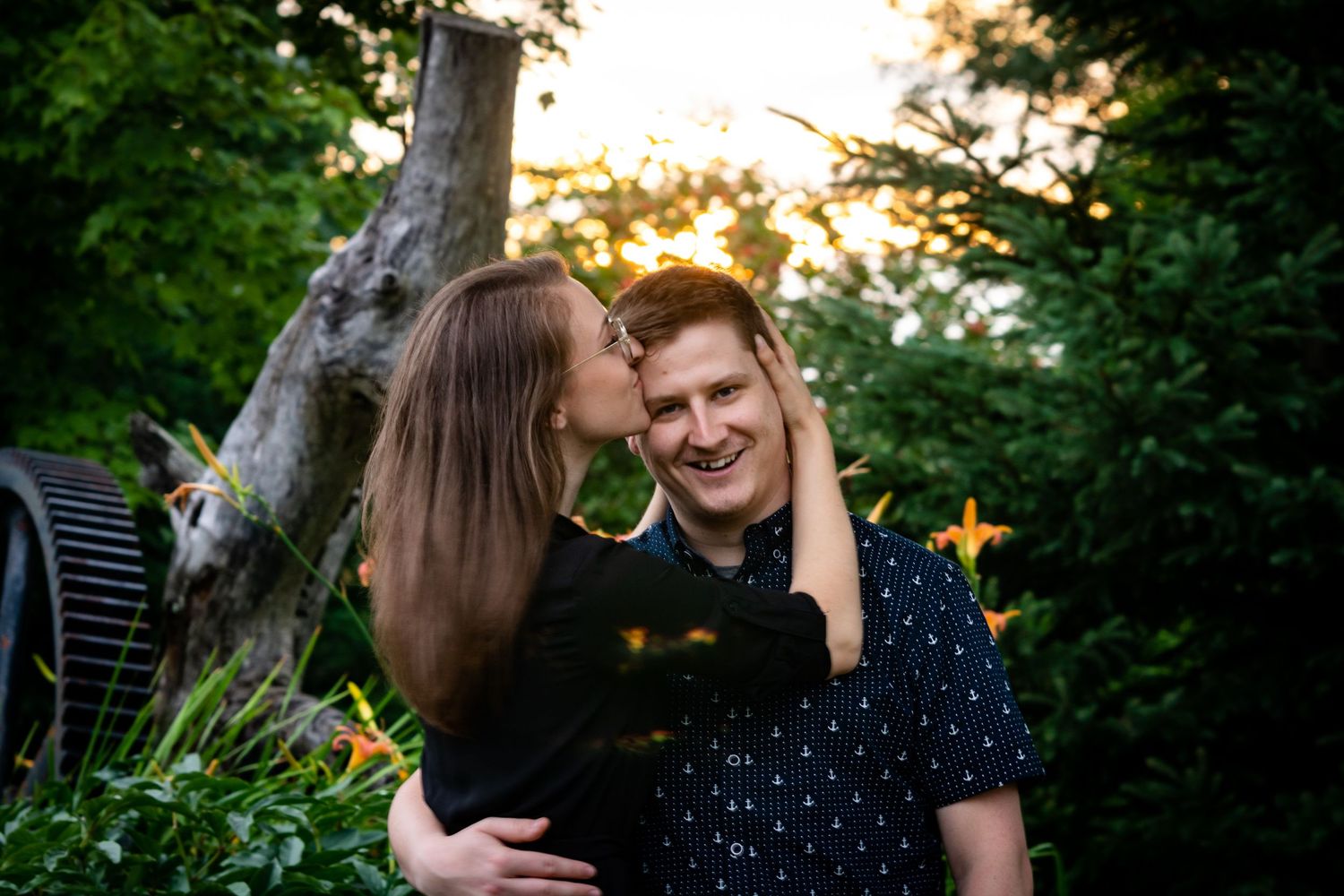 Sunset engagement session among trees with natural golden lighting.