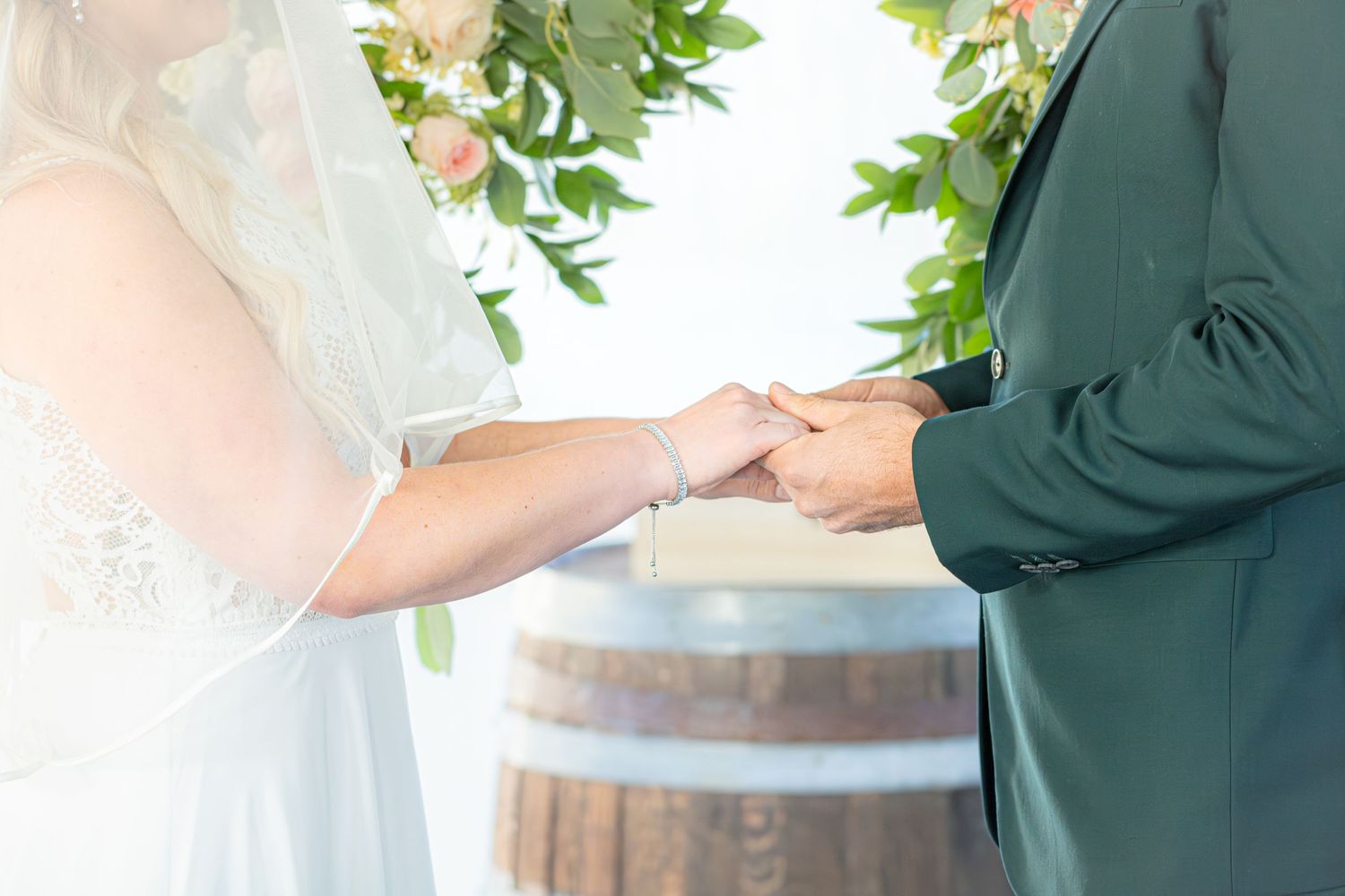 Exchange of rings during an outdoor wedding ceremony with greenery in background.