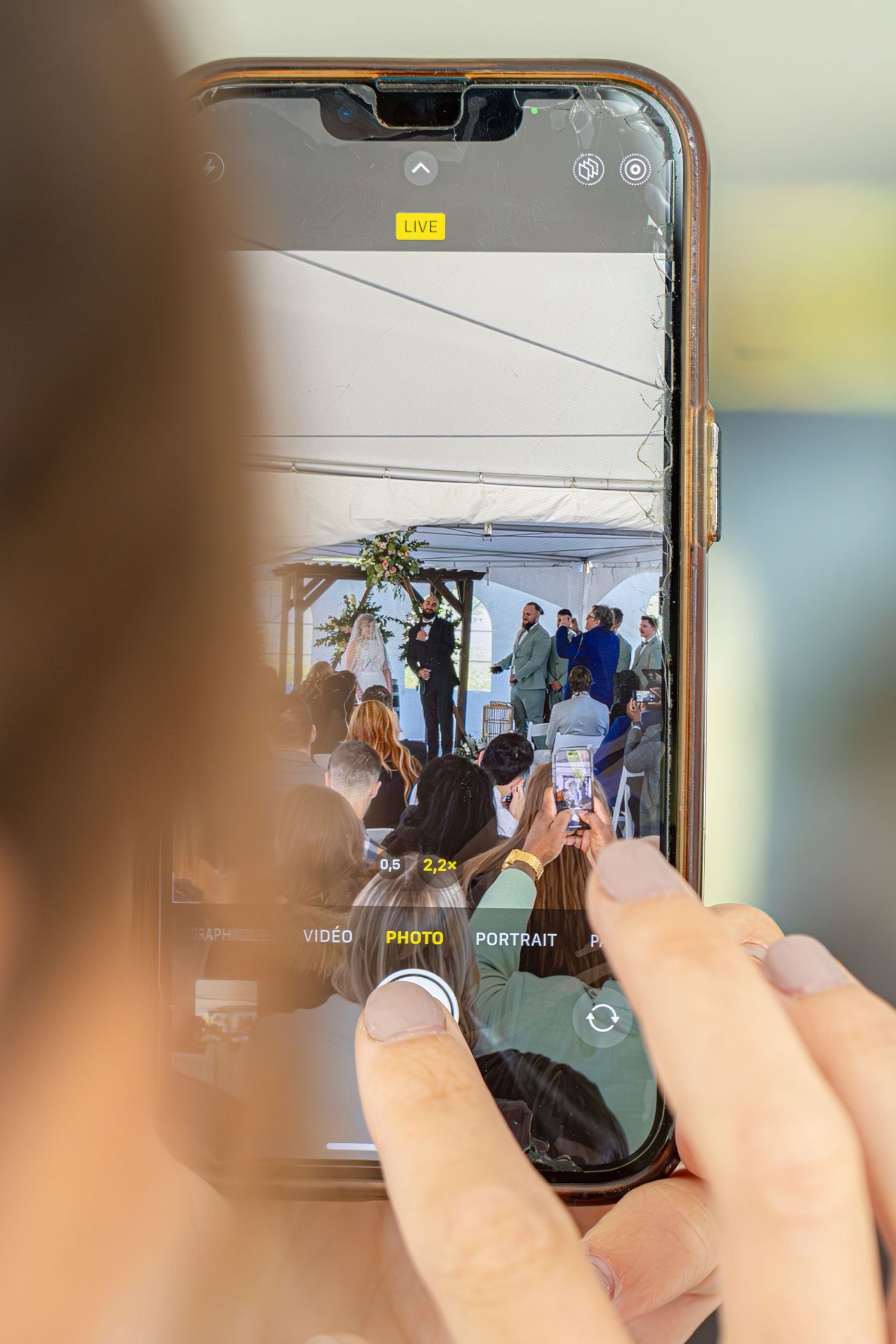 Hands holding a smartphone to capture photos at an outdoor event.