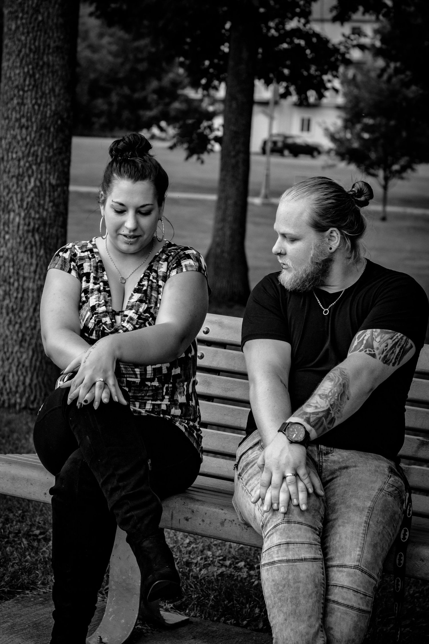 Couple sitting close together on a park bench in casual attire.