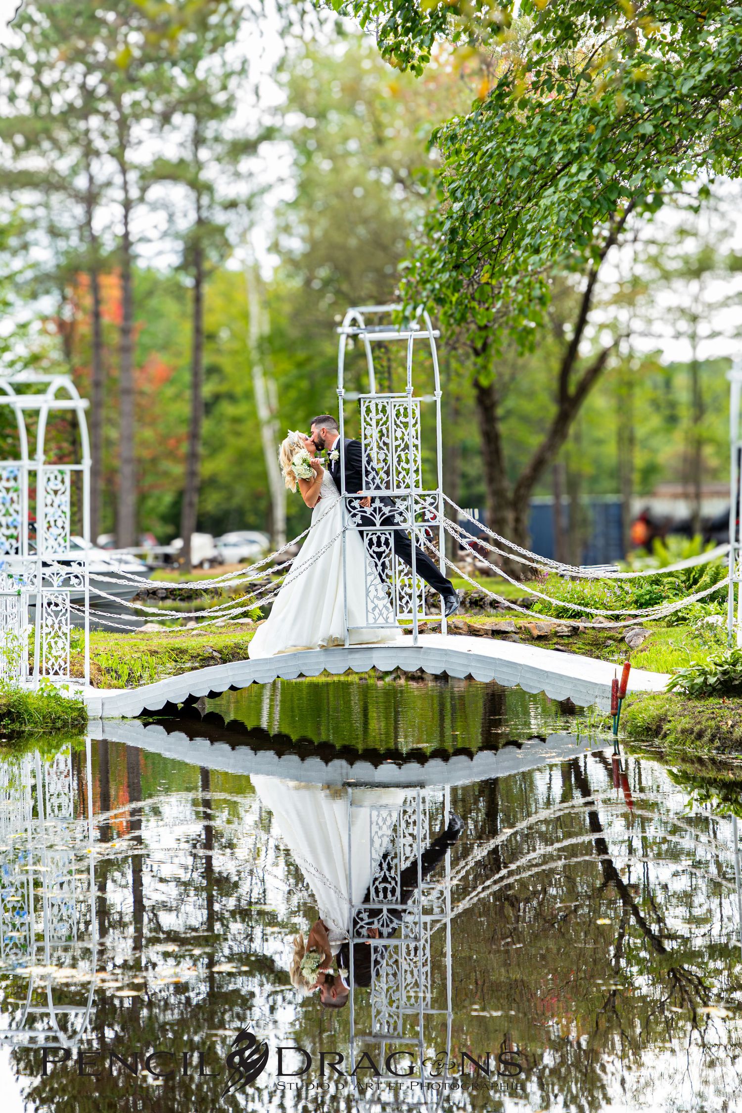 White decorative archways and bridges create a romantic reflection over still water in a garden setting.