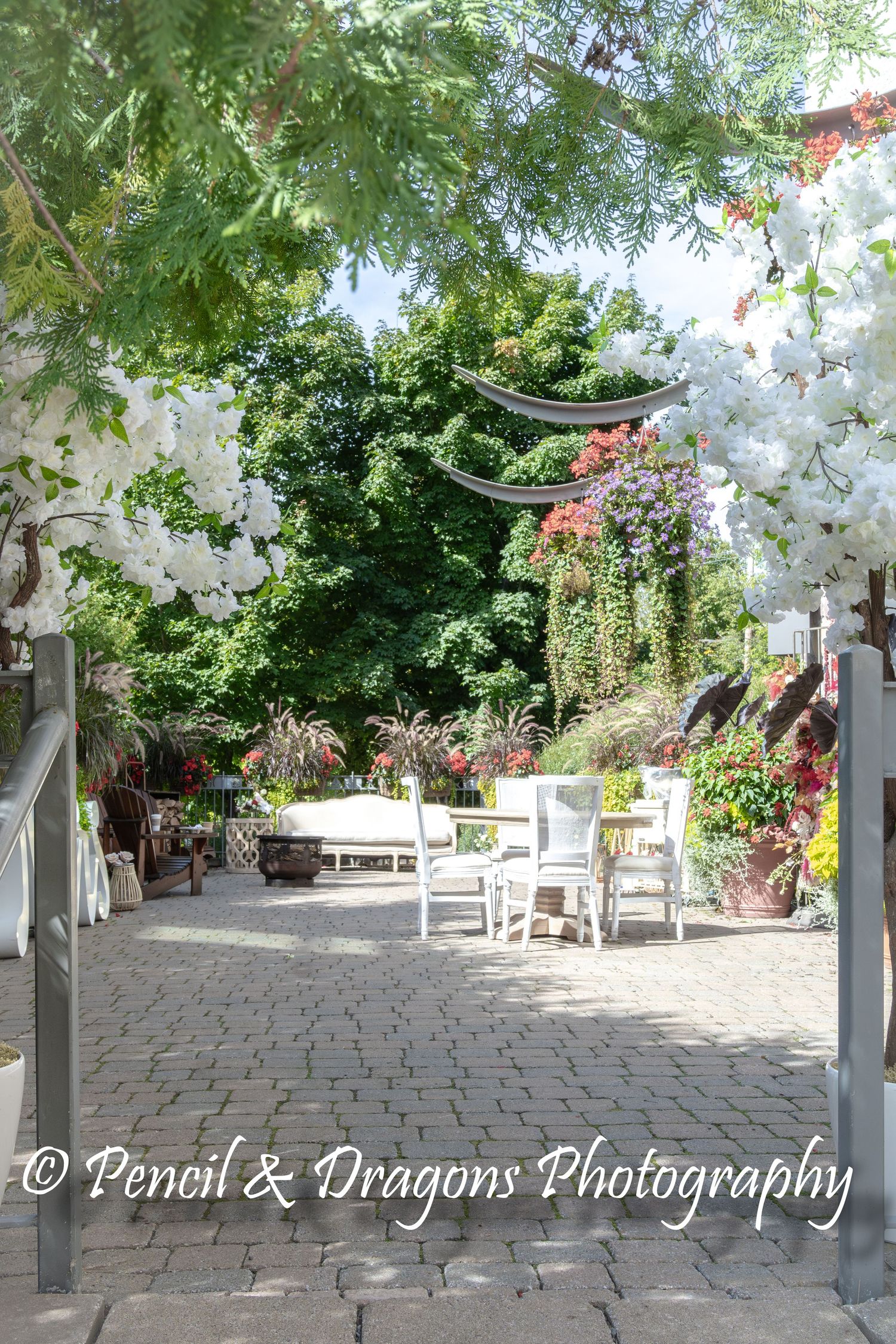 A charming garden patio with white furniture and flowering vines creating an elegant outdoor seating area.