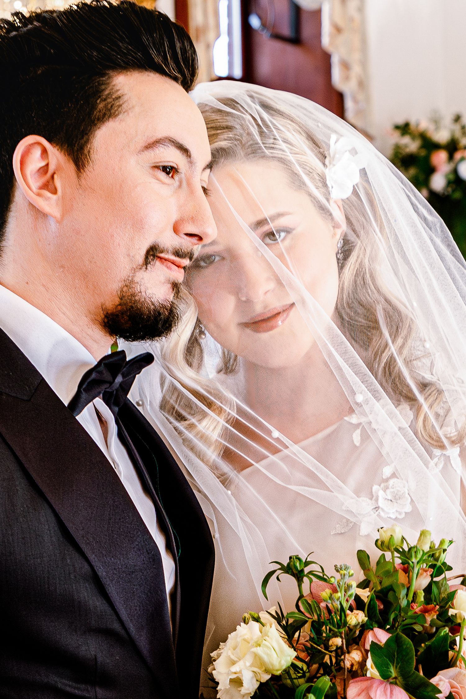 Close up of romantic moment with floral bouquet and veil details.