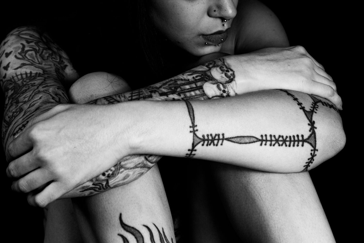 Close-up series showing detailed arm tattoos in black and white photography.