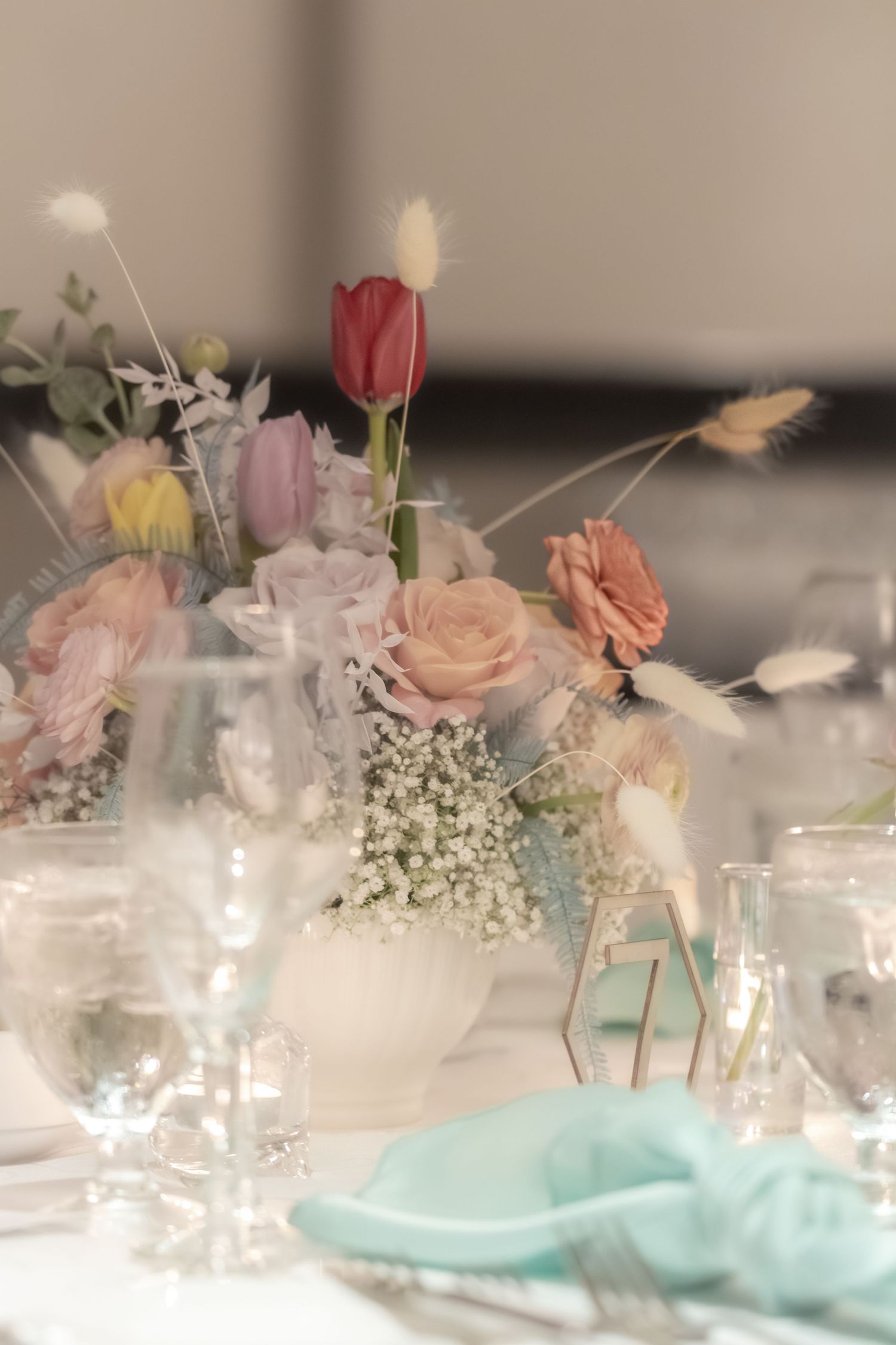 Elegant table setting with soft pink roses, baby's breath flowers, and turquoise accents in a romantic wedding reception decor.