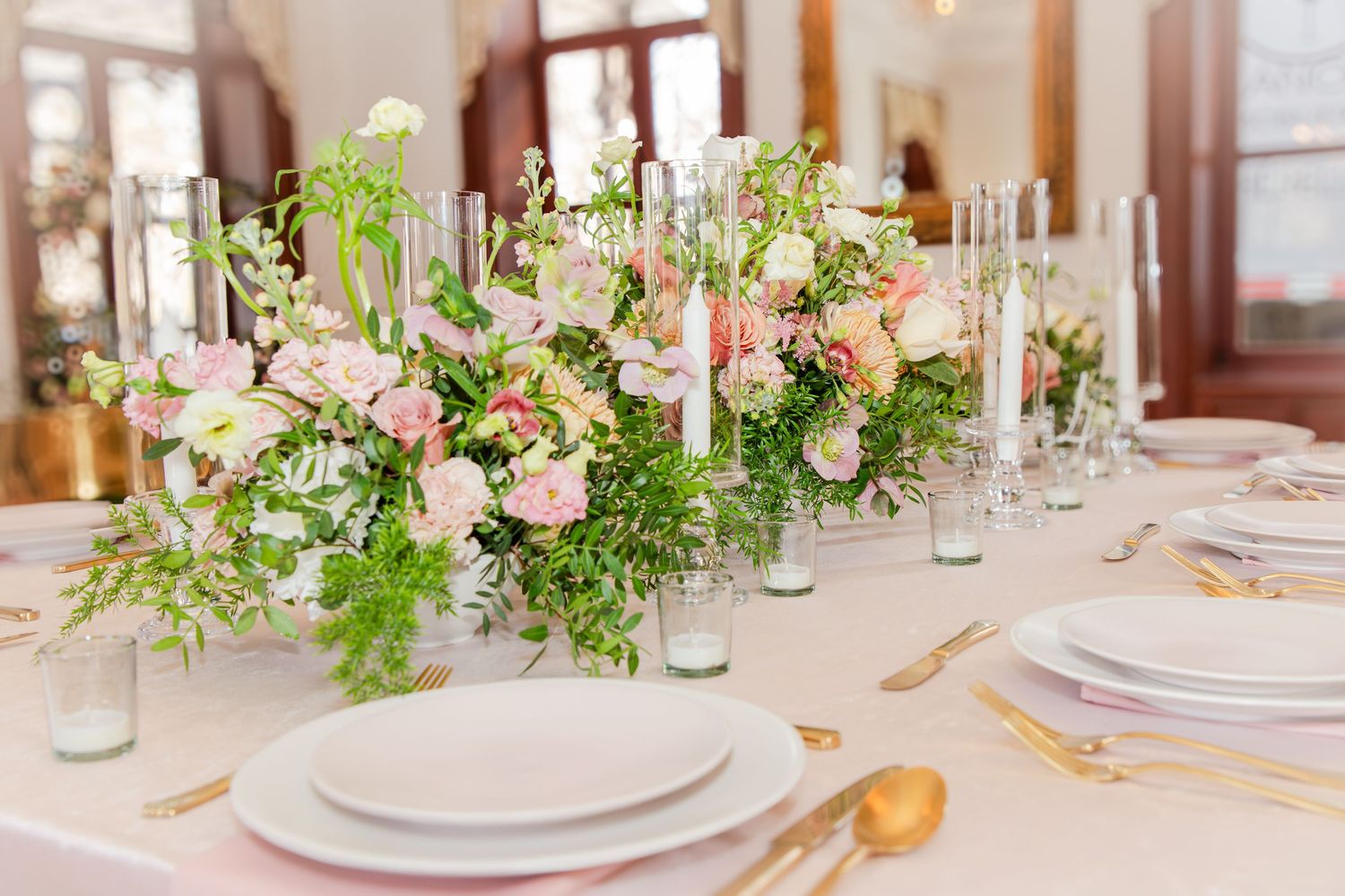 Elegant wedding reception table decorated with pink floral arrangements and candles.
