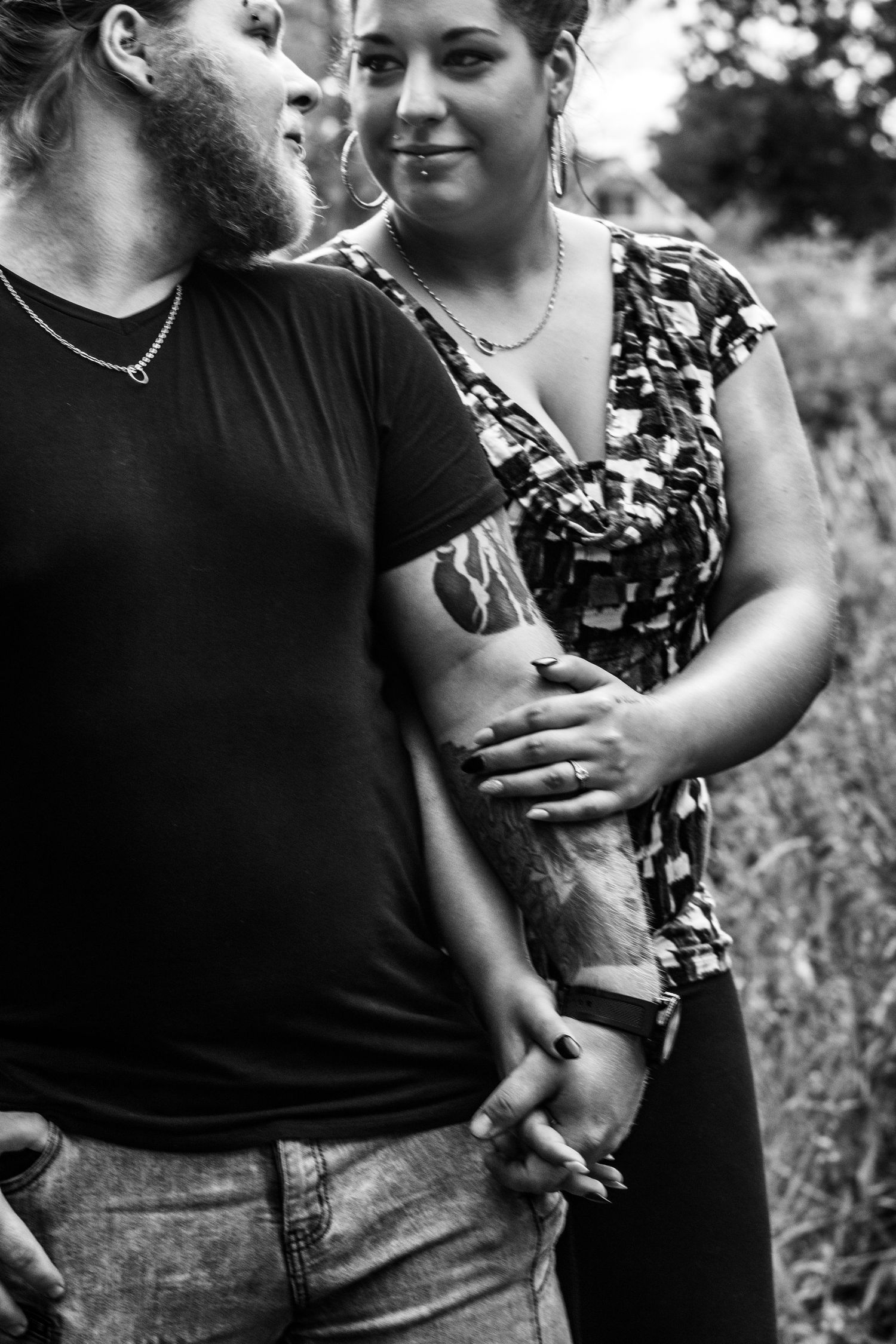 Candid black and white shots of couple embracing in natural setting.