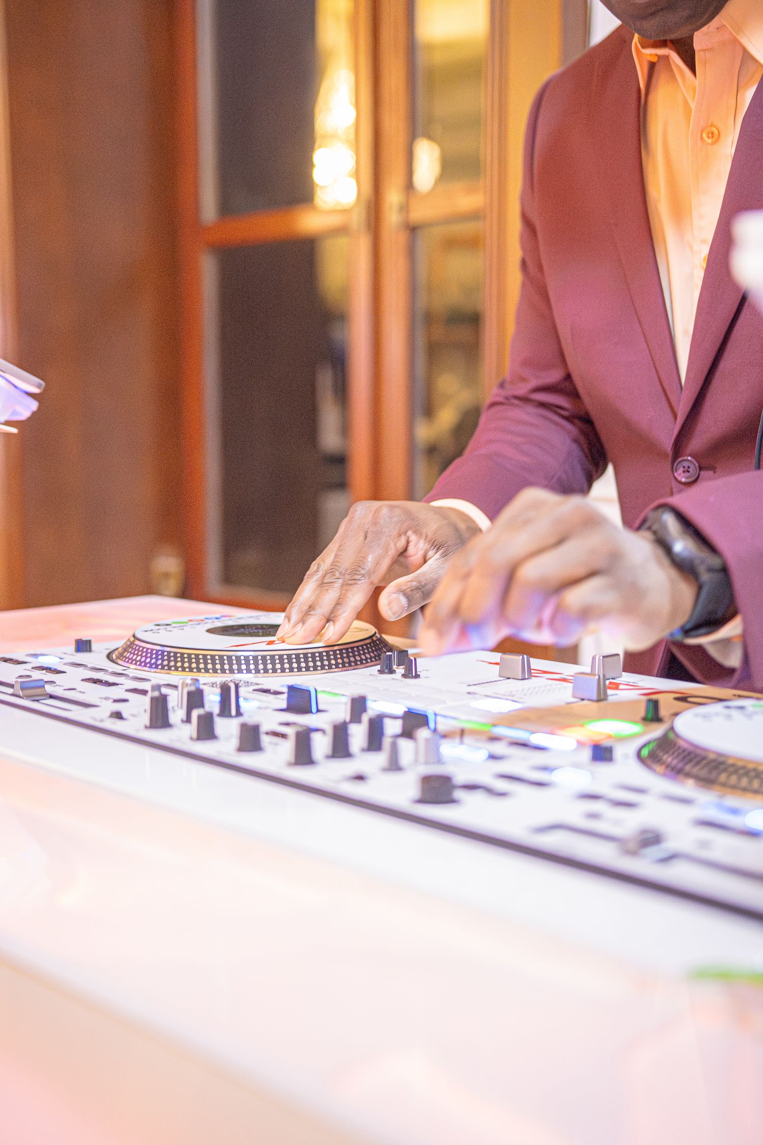 Close-up view of hands adjusting knobs and faders on a professional DJ mixing controller.