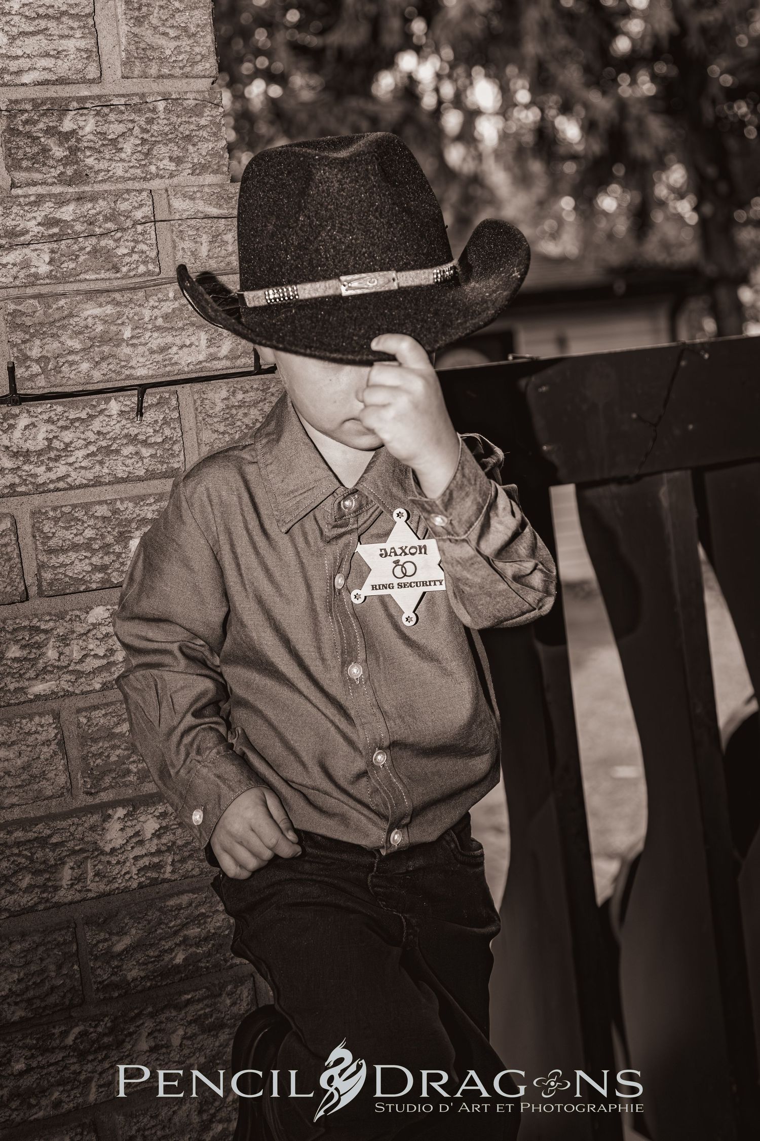 A black and white portrait of a young cowboy wearing a western hat and sheriff's badge.