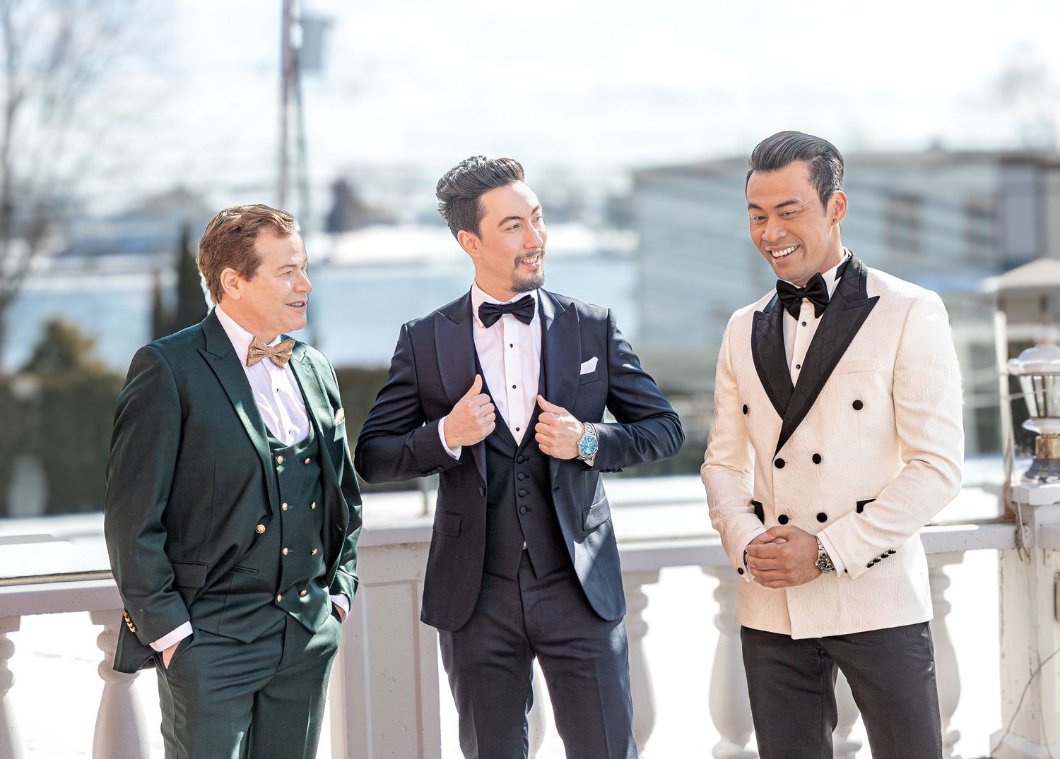 Groomsmen in formal attire posing on outdoor balcony.