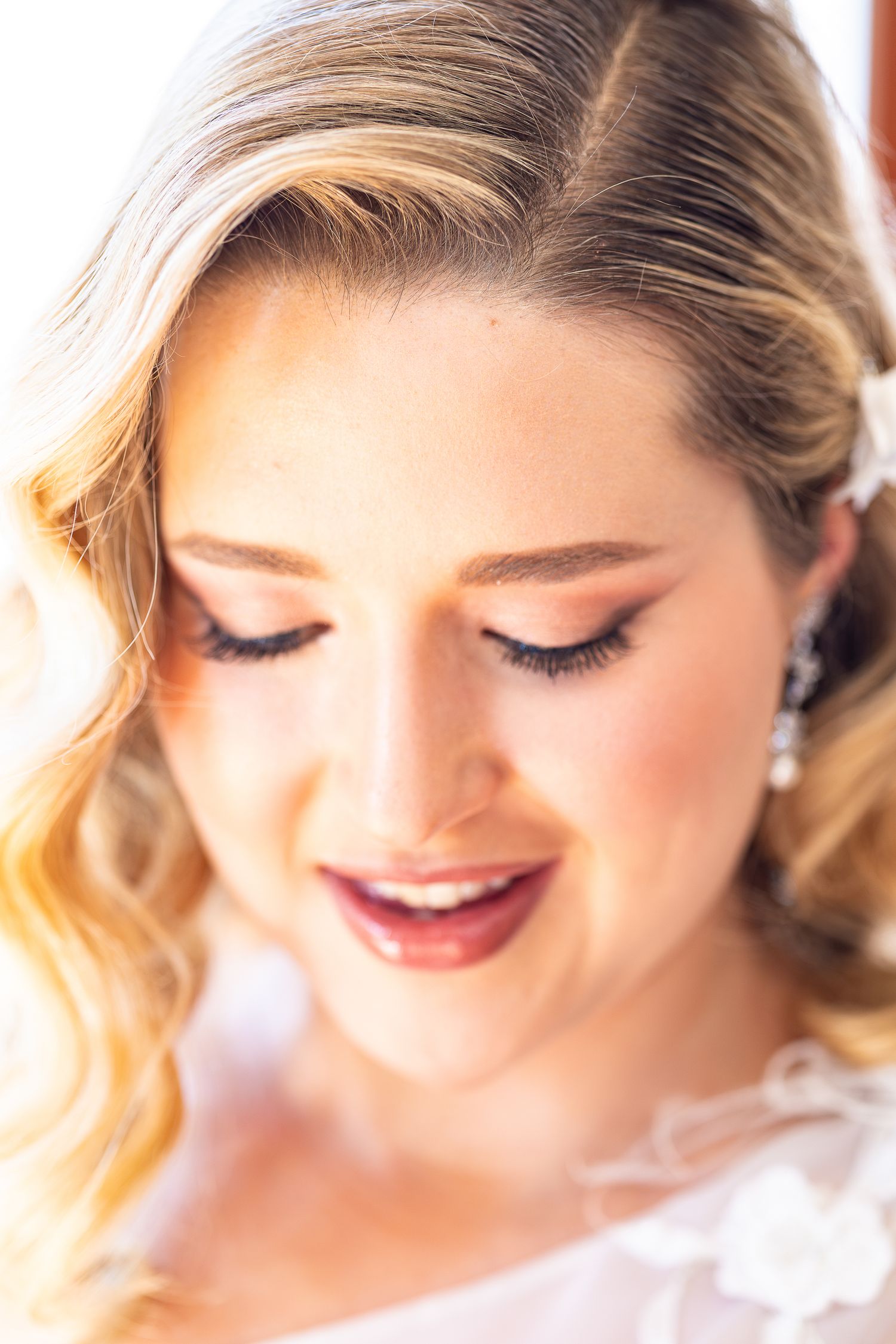 Close-up beauty shot showing soft makeup with closed eyes and pink lipstick in a romantic style.