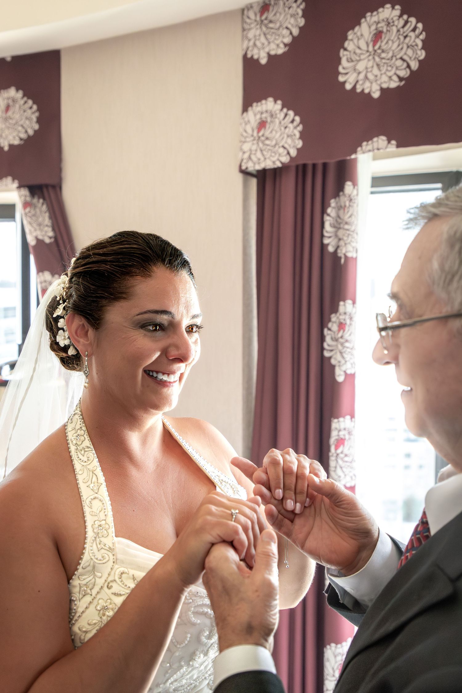 A tender moment shared between a bride in a halter wedding dress and an older man in formal attire.