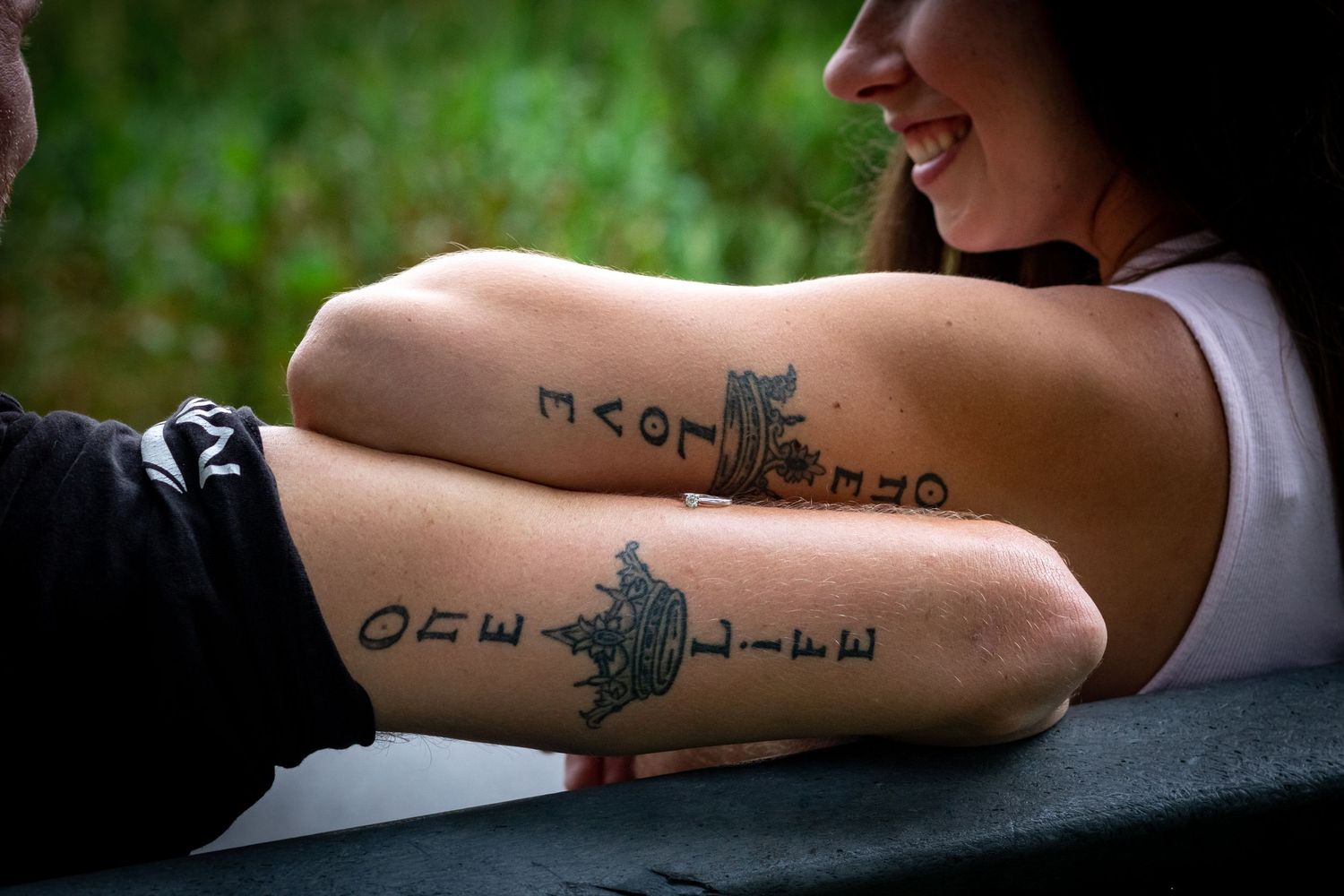 Close-up of arm tattoos showing artistic designs against dark background.