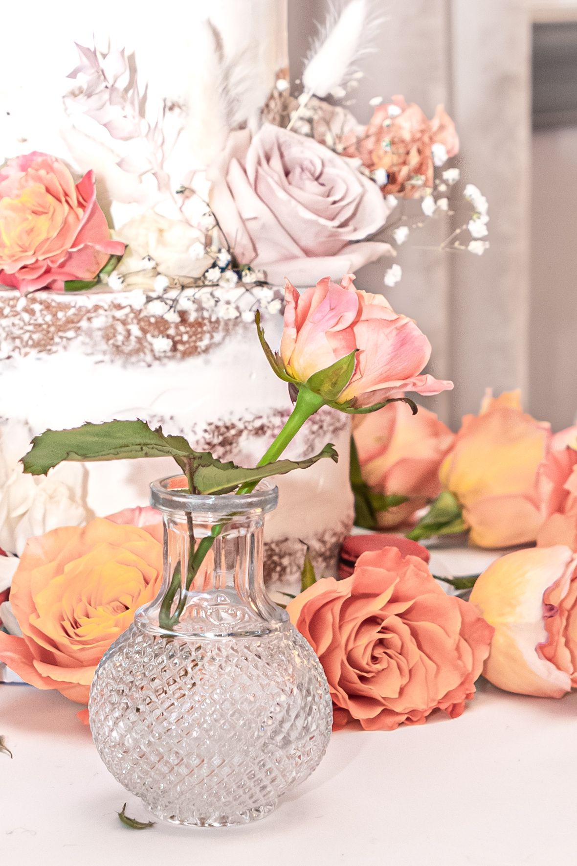 Delicate pink roses arranged in vintage cut glass vases on a white surface with soft romantic lighting.