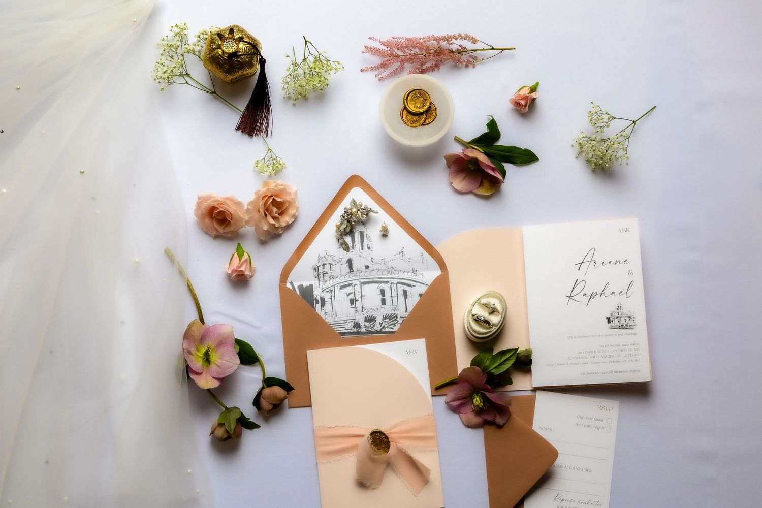 Flat lay of wedding stationery with peach envelopes, floral elements, and delicate calligraphy on a light background.