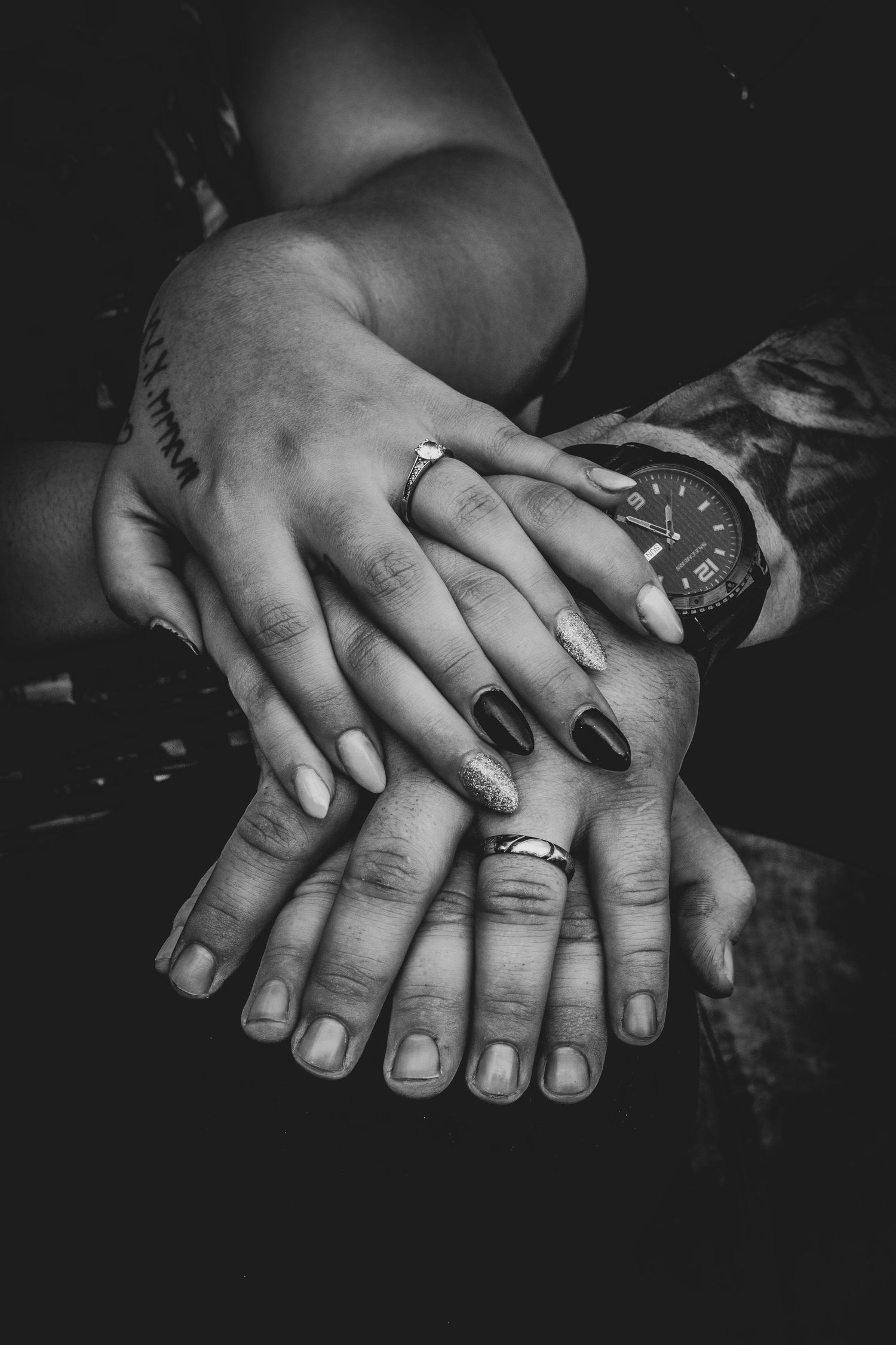 Black and white close-up of hands with engagement rings intertwined in intimate poses.
