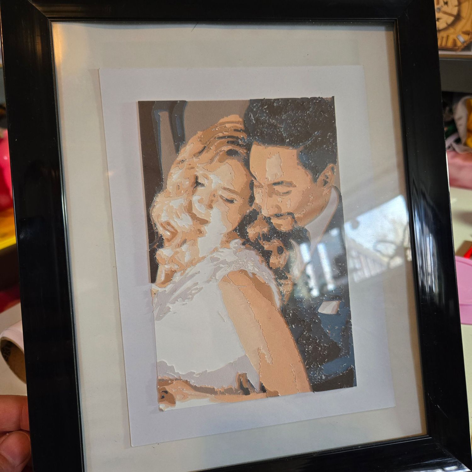 Framed mosaic art portrait of a couple embracing, displayed in a black frame with white matting.
