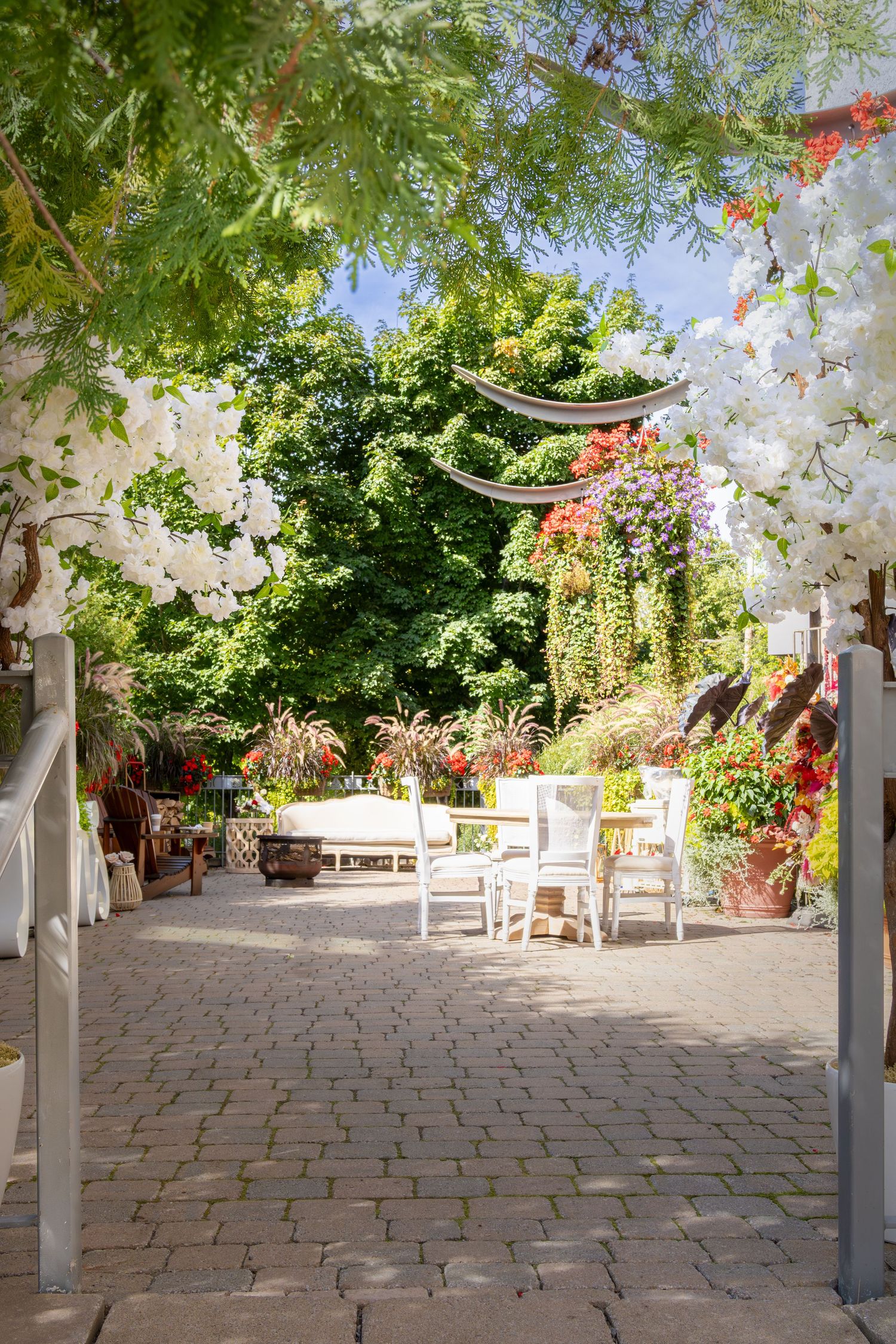 Beautiful outdoor patio setting with white furniture and flowering vines creating a romantic garden atmosphere.