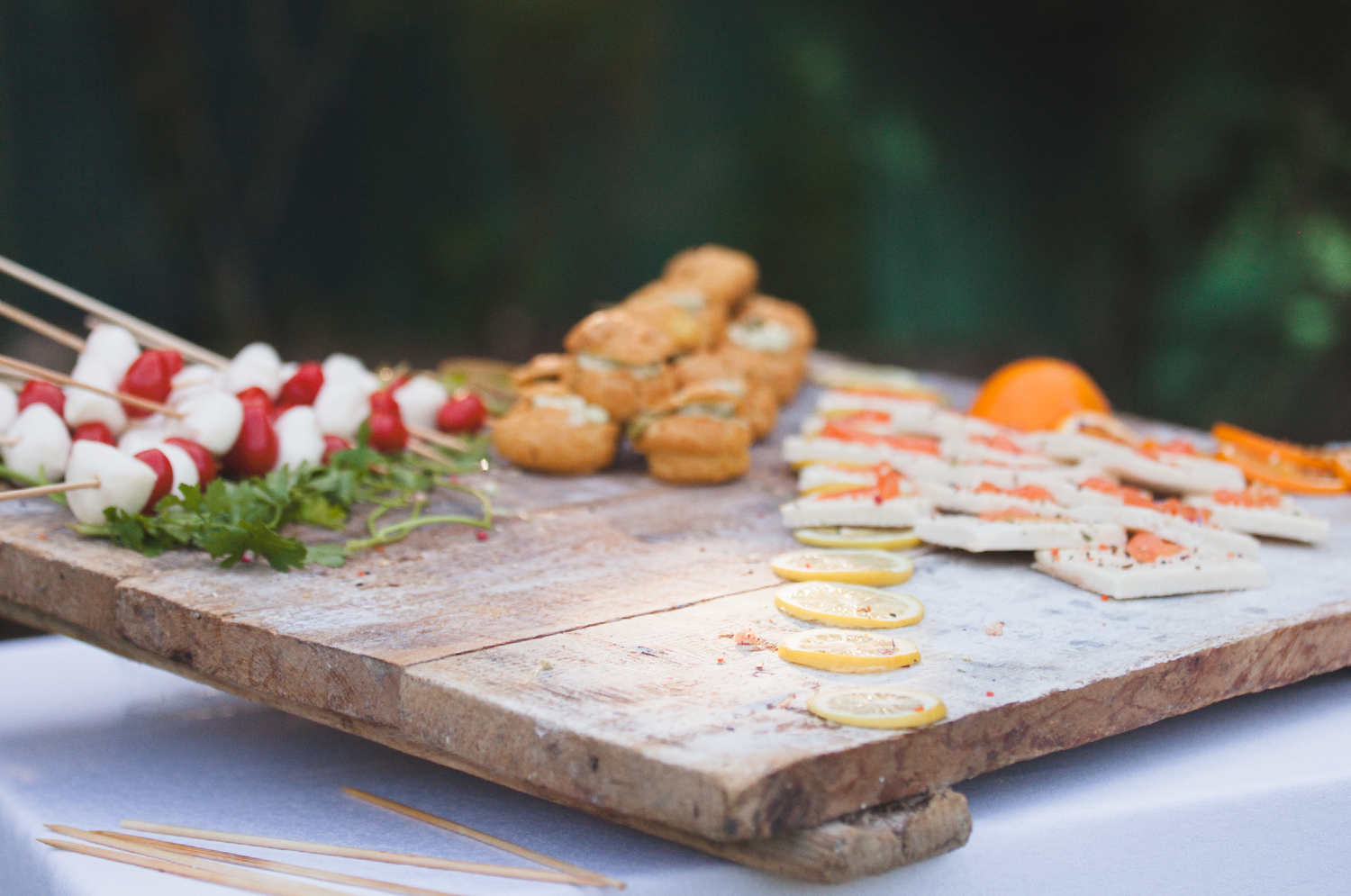 Artfully arranged appetizers and canapes on a rustic wooden serving board.