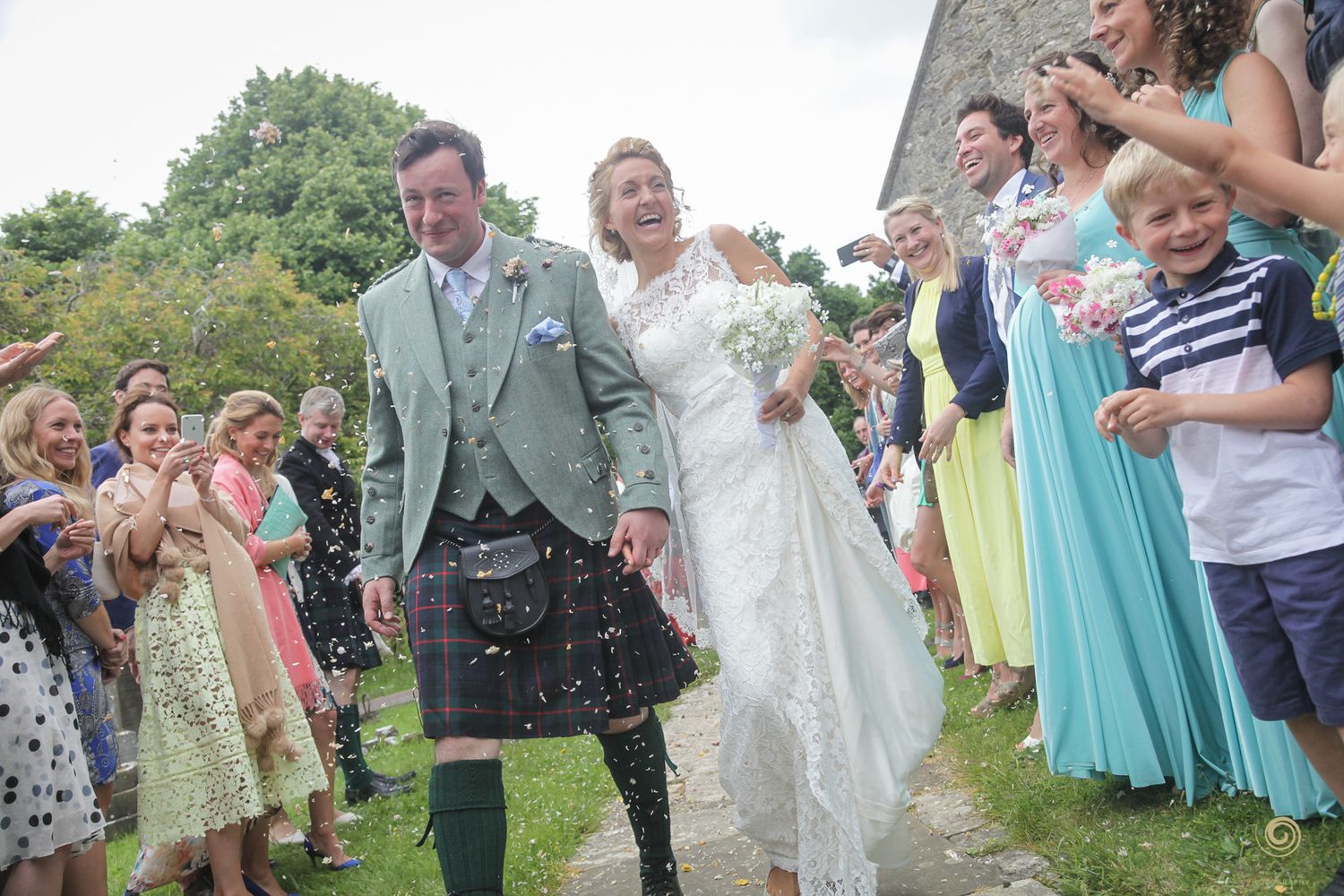 Wedding celebration with guests throwing confetti outside stone church.