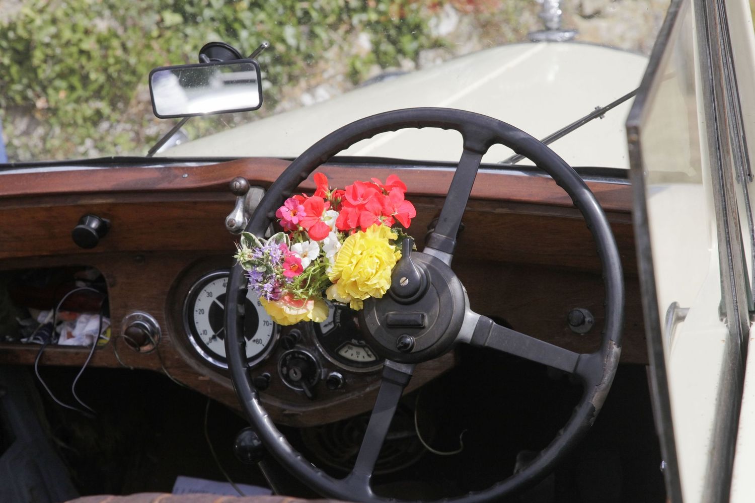 Interior view of a classic car dashboard with steering wheel and floral decorations.