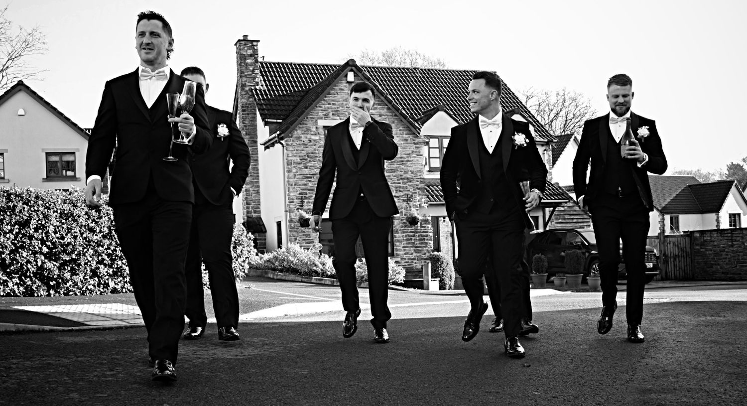 Black and white photo of wedding party walking together outdoors.
