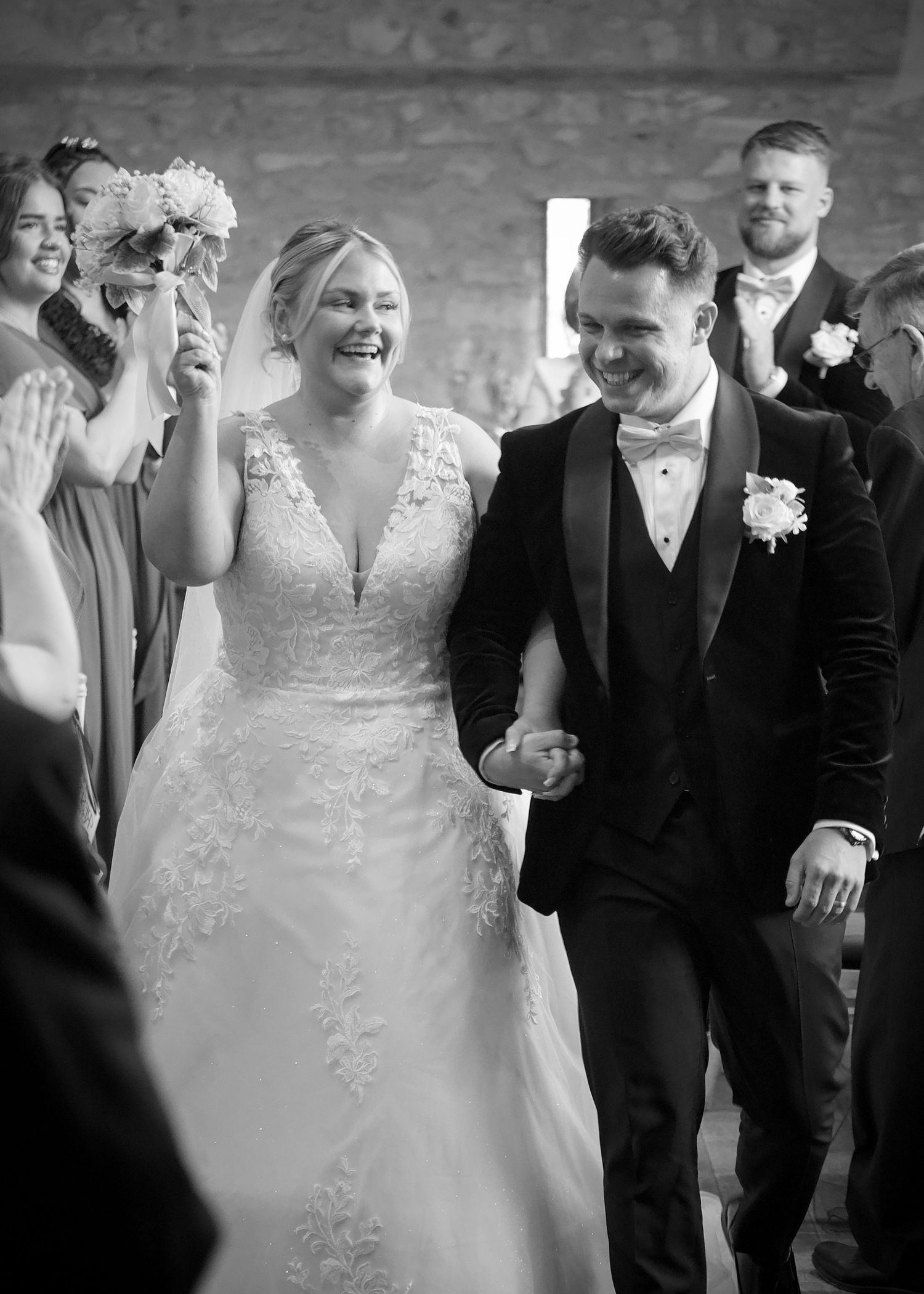Joyful wedding celebration with guests applauding in a rustic stone venue.